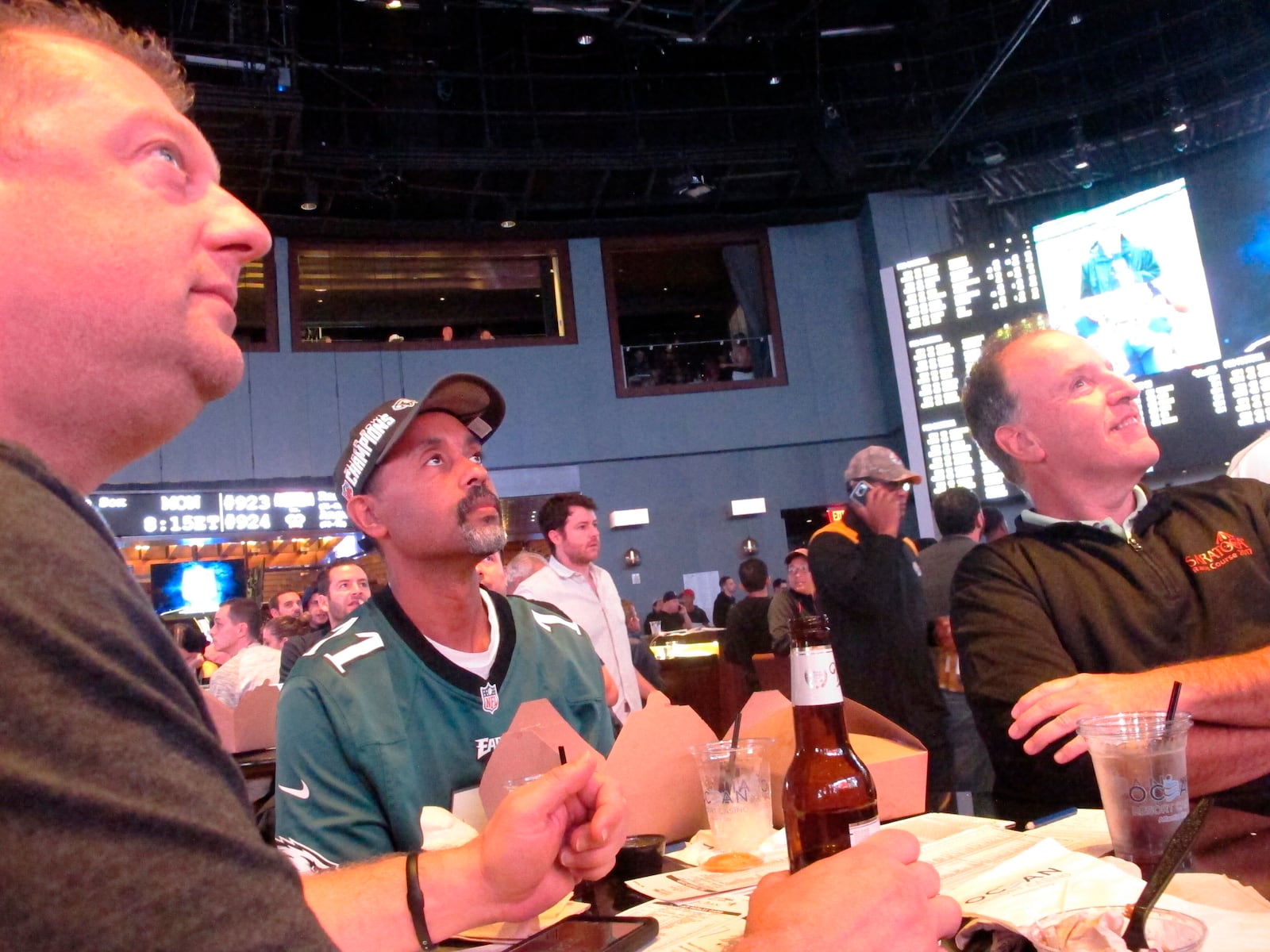 In this Sept. 9, 2019 photo, football fans watch the action on-wall-mounted video screens in the sports betting lounge at the Ocean Casino Resort in Atlantic City, N.J. The coronavirus outbreak has added new wrinkles for bettors this year, but even so, the nation's sportsbooks expect a record year of bets on football in 2020 from an antsy public that has been cooped up for months amid the pandemic. (AP Photo/Wayne Parry)