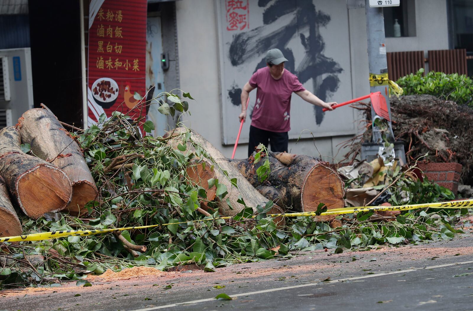 A woman clears debris in the aftermath of Typhoon Kong-rey in Taipei, Taiwan, Friday, Nov. 1, 2024. (AP Photo/Chiang Ying-ying)