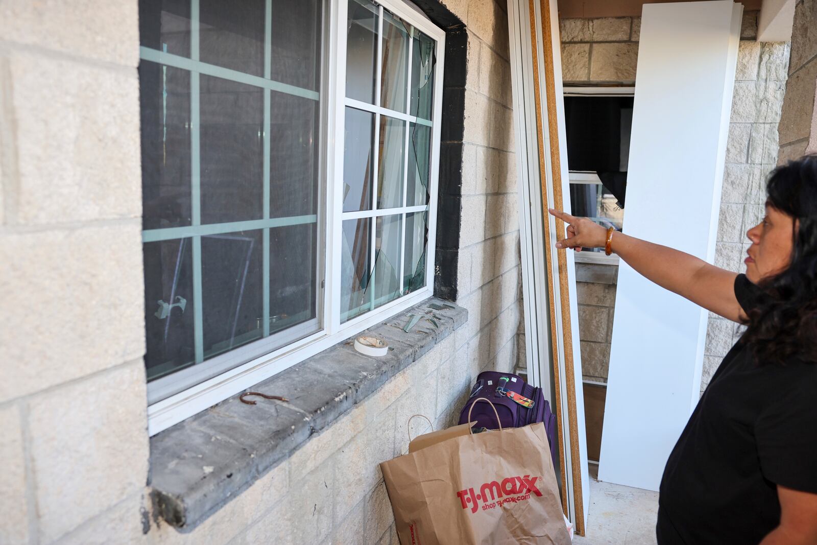 Evelyn Paguirigan points to broken windows at her home across the street from where a New Year's Eve fireworks explosion killed and injured people in Honolulu, on Wednesday, Jan. 1, 2025. (AP Photo/Marco Garcia)