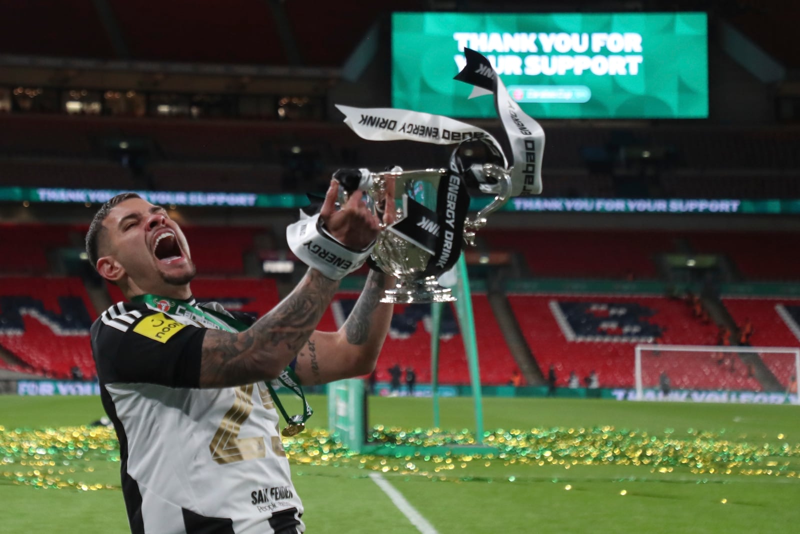 Newcastle's Bruno Guimaraes lifts the trophy after winning the EFL Cup final soccer match between Liverpool and Newcastle at Wembley Stadium in London, Sunday, March 16, 2025. (AP Photo/Scott Heppell)