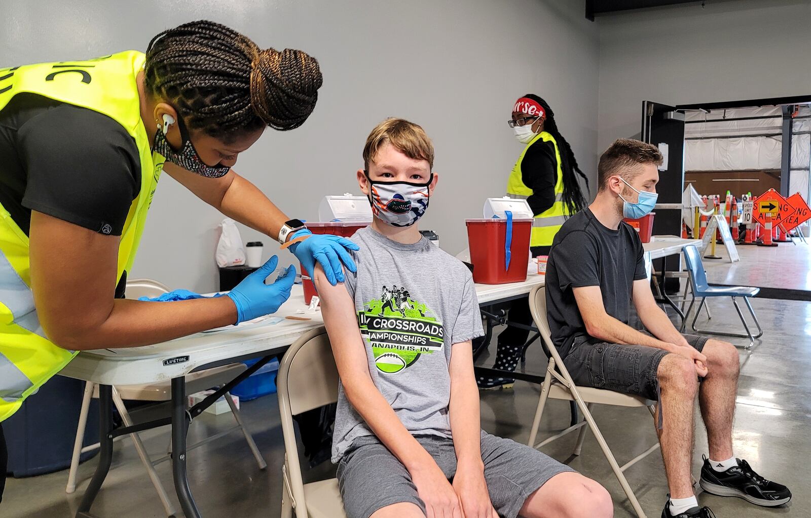 Chase Dwyer, 12, gets his COVID-19 vaccine administered by nurse Ronisha Reid as his brother, Brendan Dwyer, 17, waits for his turn in June at the Butler County Fairgrounds. The Ohio Department of Health is strongly recommending that unvaccinated students and staff wear masks when school starts. NICK GRAHAM / STAFF