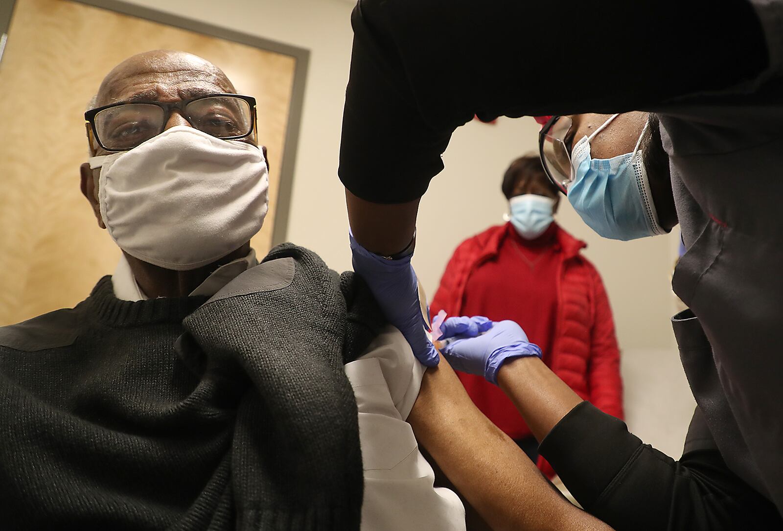 Former Springfield Police Chief Roger Evans gets a COVID-19 vaccine injection from Sherita Bloxom, a nurse at the Rocking Horse Center Thursday as his wife, Sharon, waits in the background. The Rocking Horse Center started giving out the vaccine to seniors over 80 Thursday. BILL LACKEY/STAFF