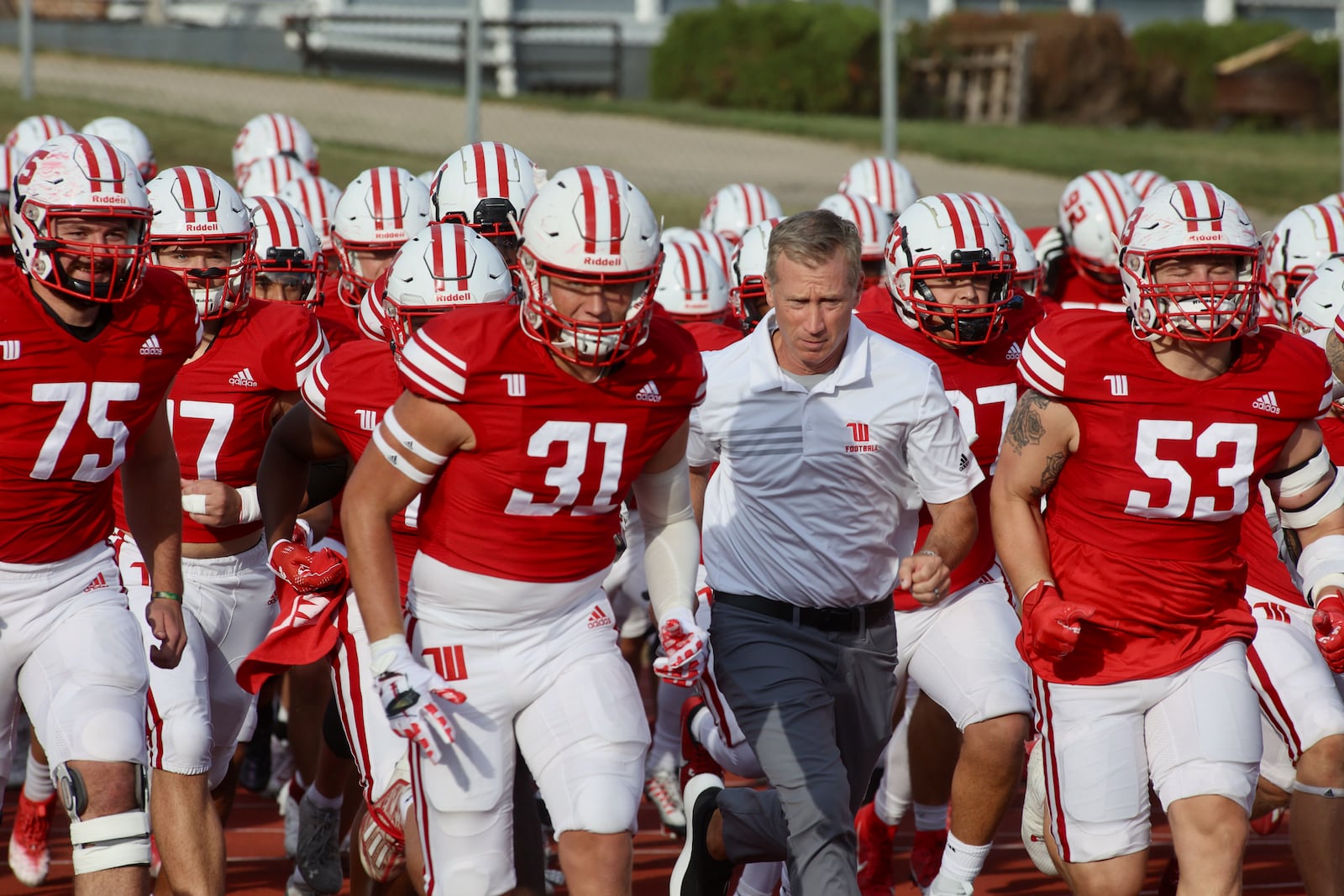 Wittenberg players and coach Jim Collins take the field before a game against Kenyon on Saturday, Sept. 16, 2023, at Edwards-Maurer Field in Springfield. David Jablonski/Staff