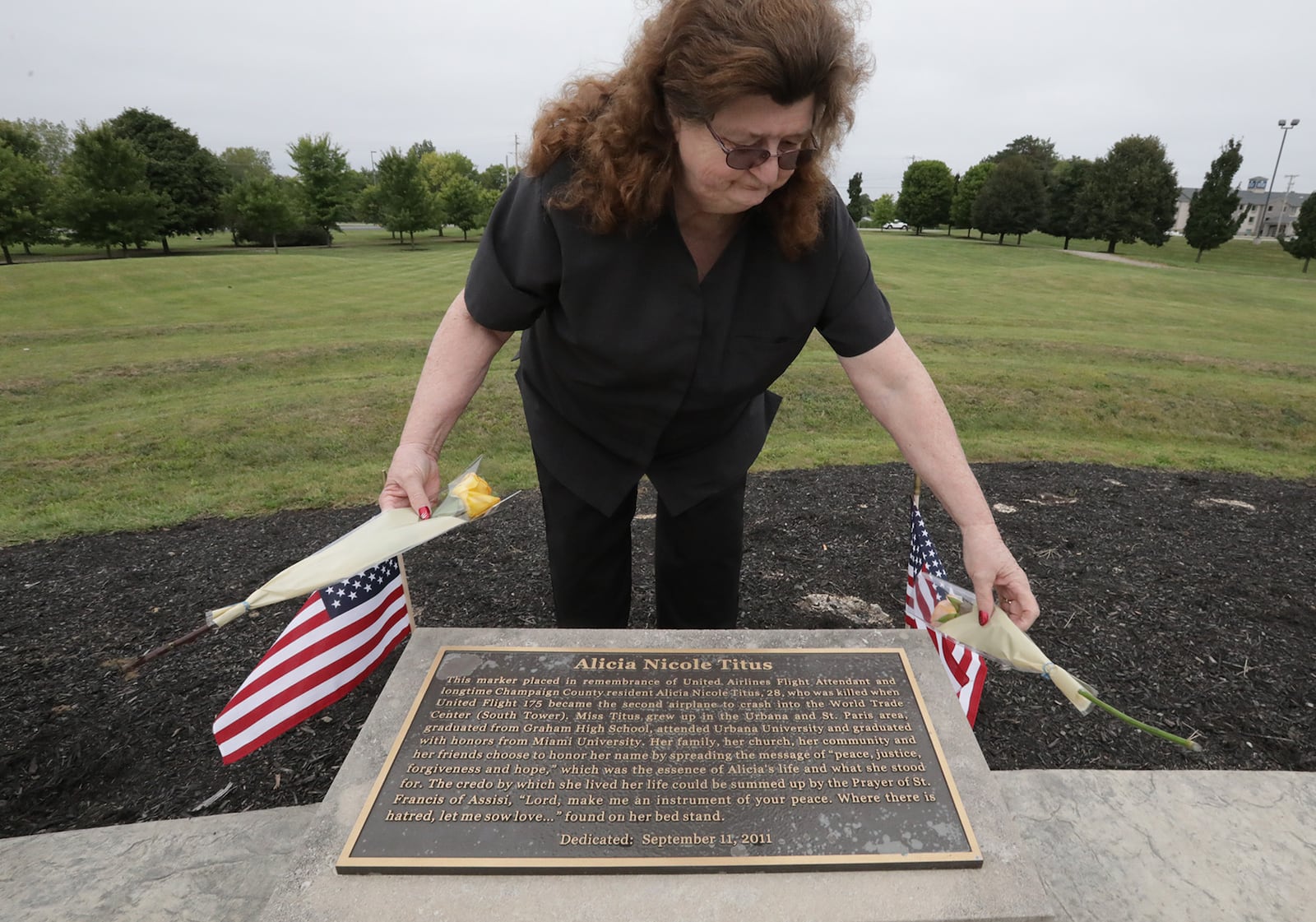 Patty Fink, an aunt of Champaign County native Alicia Titus who was a flight attendant on the plane that struck the south World Trade Center tower, places two yellow roses on a memorial to Alicia at Freedom Grove in Urbana Friday. BILL LACKEY/STAFF