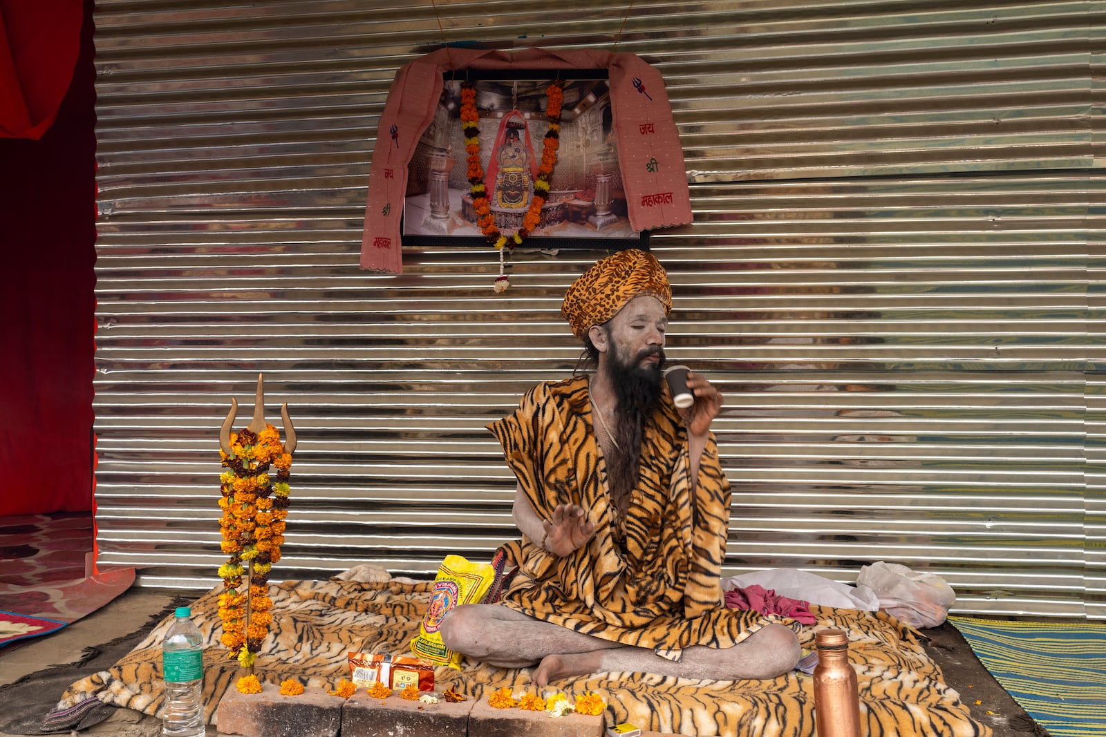 A Hindu holy man sips tea at his makeshift living quarters at the confluence of the Ganges, the Yamuna and the mythical Saraswati rivers, a day before the official beginning of the 45-day-long Maha Kumbh festival, in Prayagraj, India, Sunday, Jan. 12, 2025. (AP Photo/Ashwini Bhatia)