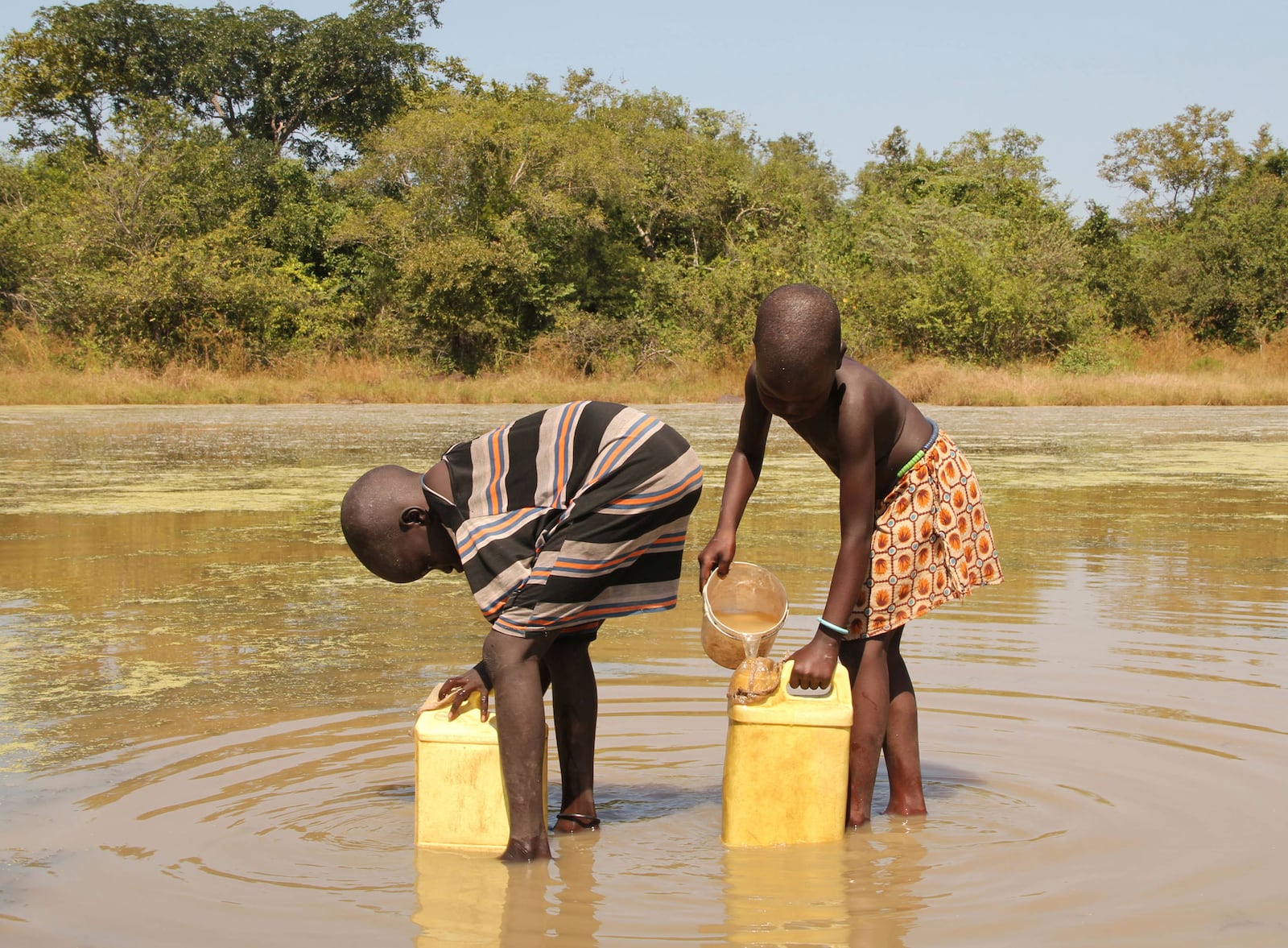 FILE - In this Nov. 4, 2010 photo, children collect drinking water from a pond using filters provided to them by The Carter Center's guinea worm eradication program in the remote village of Lengjak, in Awerial County, Lakes State, Southern Sudan. (AP Photo/Maggie Fick, File)