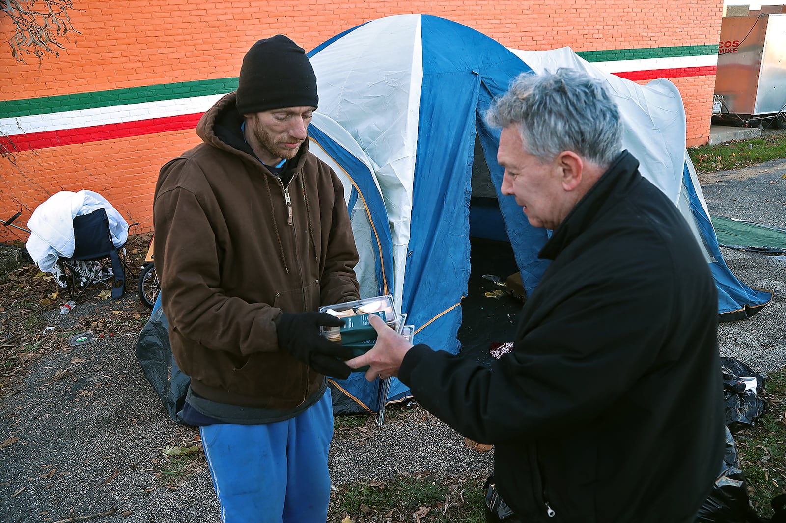 Fred Stegner, the president of the Springfield Soup Kitchen, gives food to a homeless man and his pregnant wife who are living in a tent across the street from the Soup Kitchen in November.  BILL LACKEY/STAFF