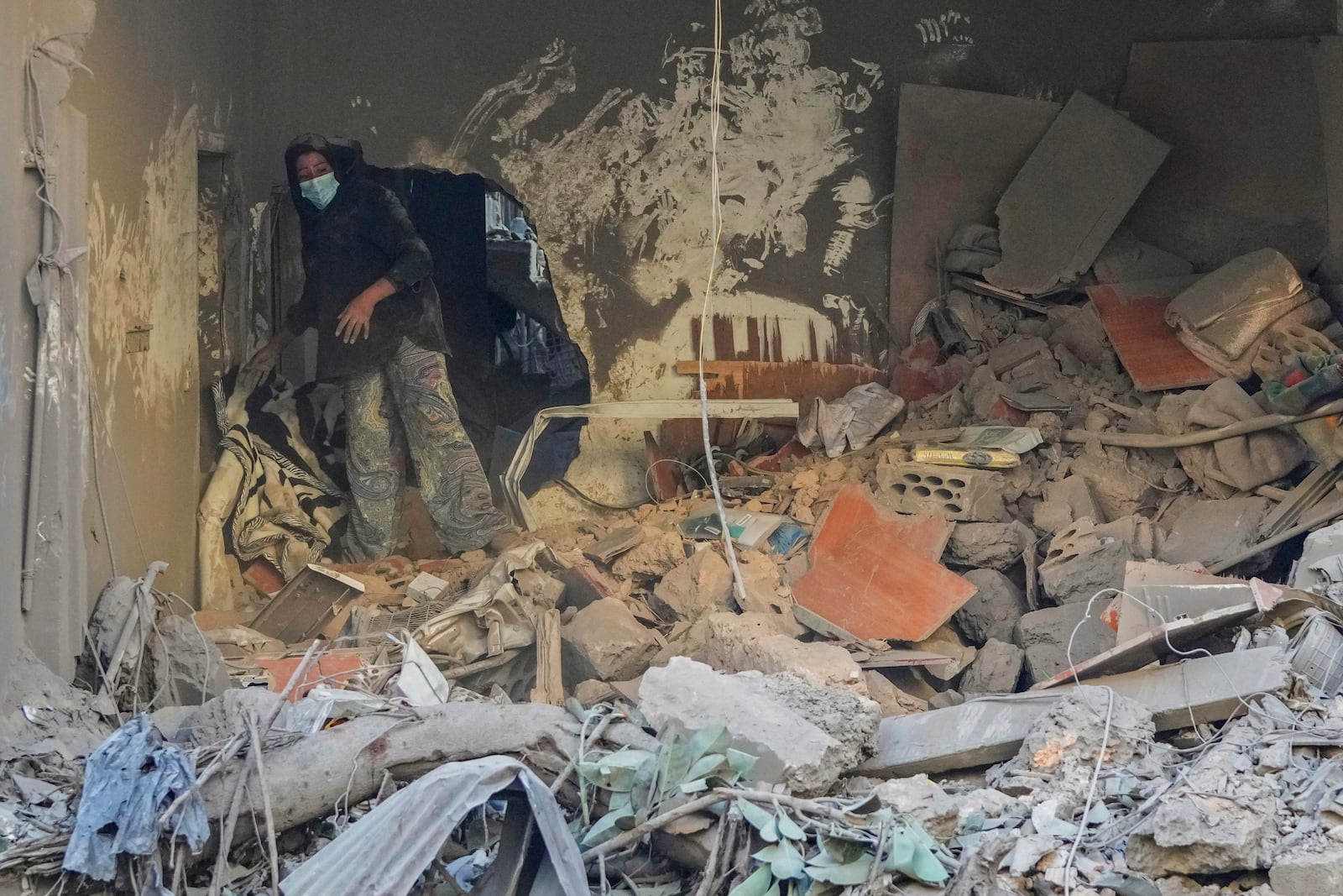 A resident of a building damaged in an Israeli airstrike returns to collect her family's belongings at the site of Thursday's Israeli airstrike in Beirut, Lebanon, Friday, Oct. 11, 2024. (AP Photo/Hassan Ammar)