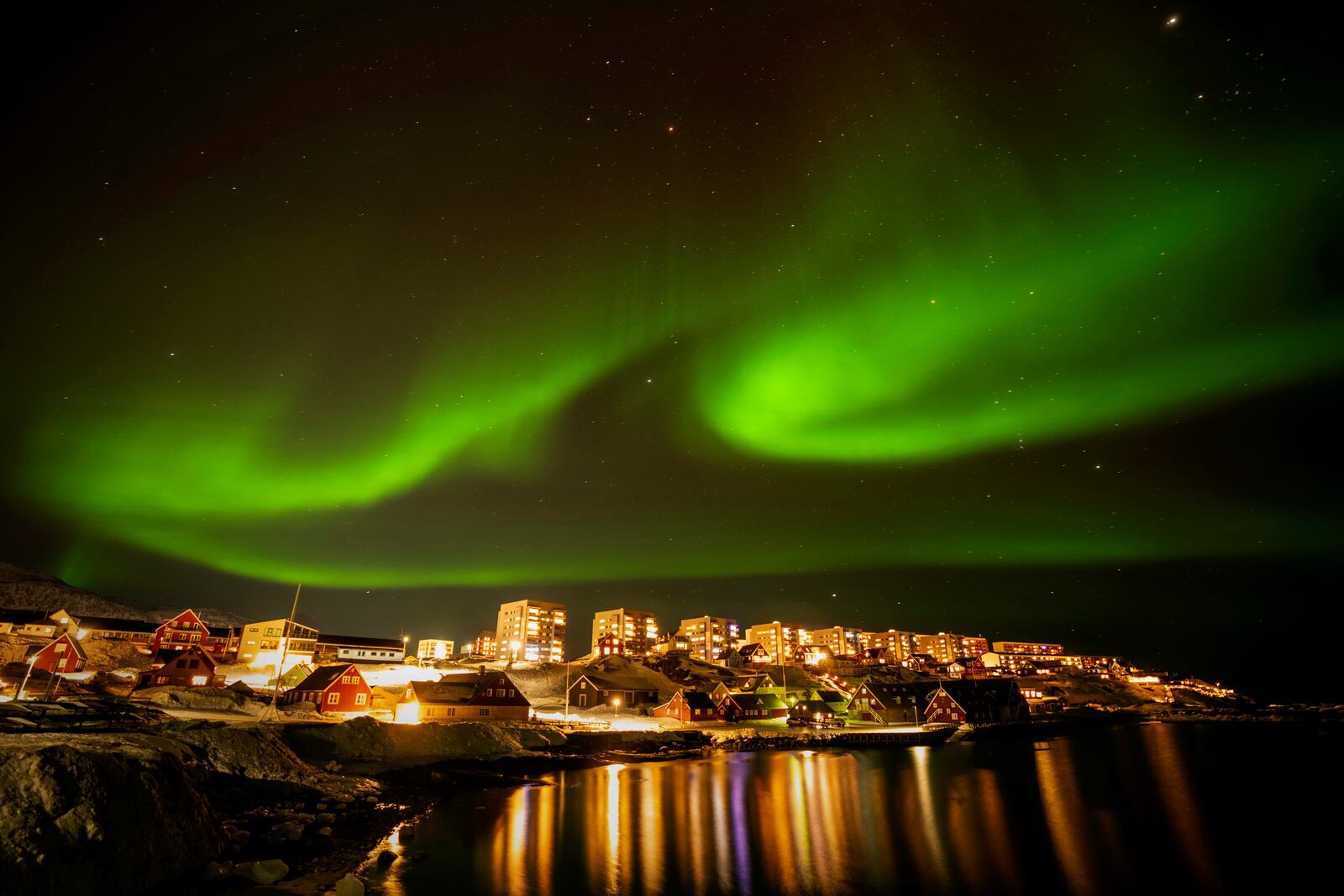 The northern lights appear over homes in Nuuk, Greenland, Monday, Feb. 17, 2025. (AP Photo/Emilio Morenatti)