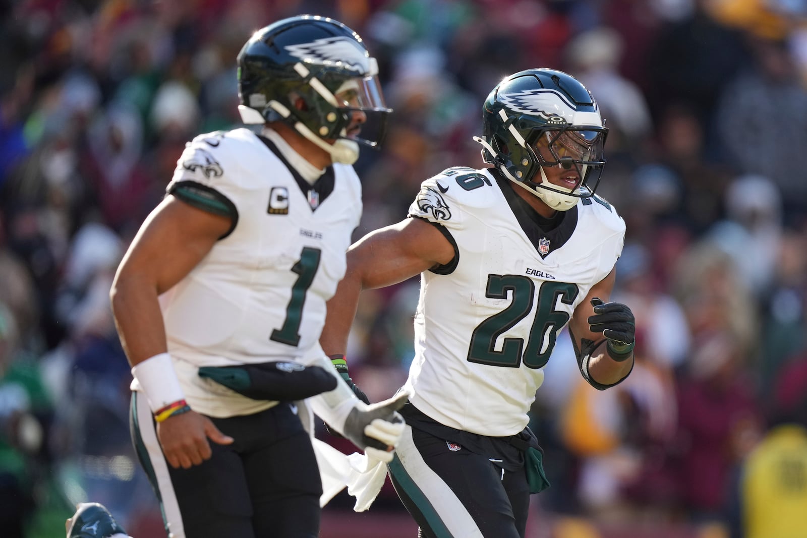 Philadelphia Eagles running back Saquon Barkley (26) celebrating his touchdown with his teammate Philadelphia Eagles quarterback Jalen Hurts (1) during the first half of an NFL football game against the Washington Commanders, Sunday, Dec. 22, 2024, in Landover, Md. (AP Photo/Stephanie Scarbrough)