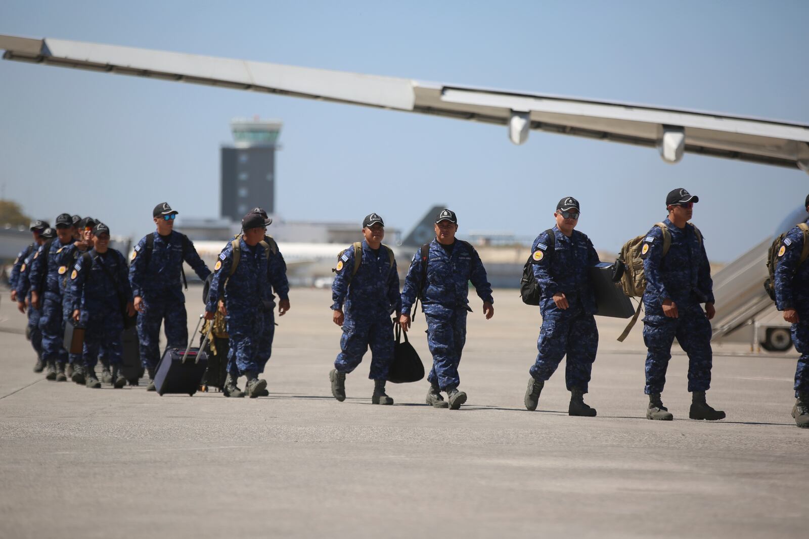 Members of a U.N.-backed El Salvadoran police force walk on the tarmac of the Toussaint Louverture International Airport after landing in Port-au-Prince, Haiti, Tuesday, Feb. 4, 2025.(AP Photo/Odelyn Joseph)