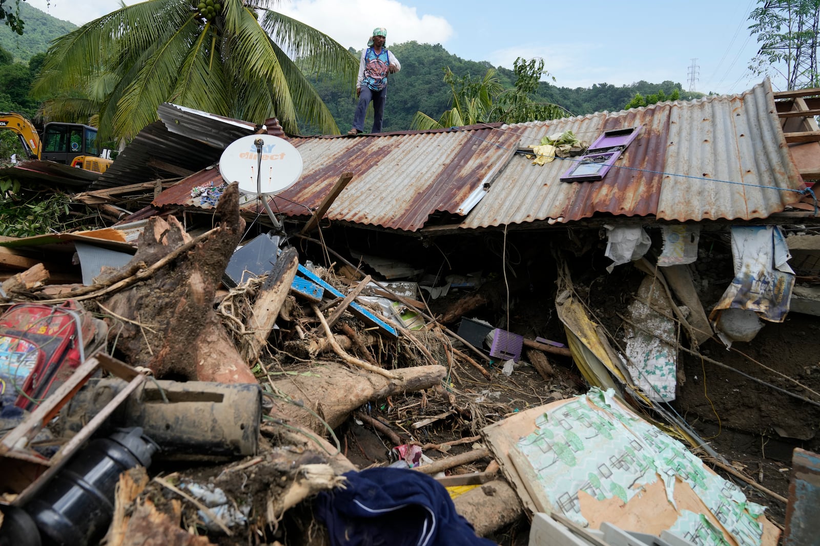 Marcelino Aringo stands on top of a damaged house after a landslide triggered by Tropical Storm Trami recently struck Talisay, Batangas province, Philippines, Saturday, Oct. 26, 2024 . (AP Photo/Aaron Favila)