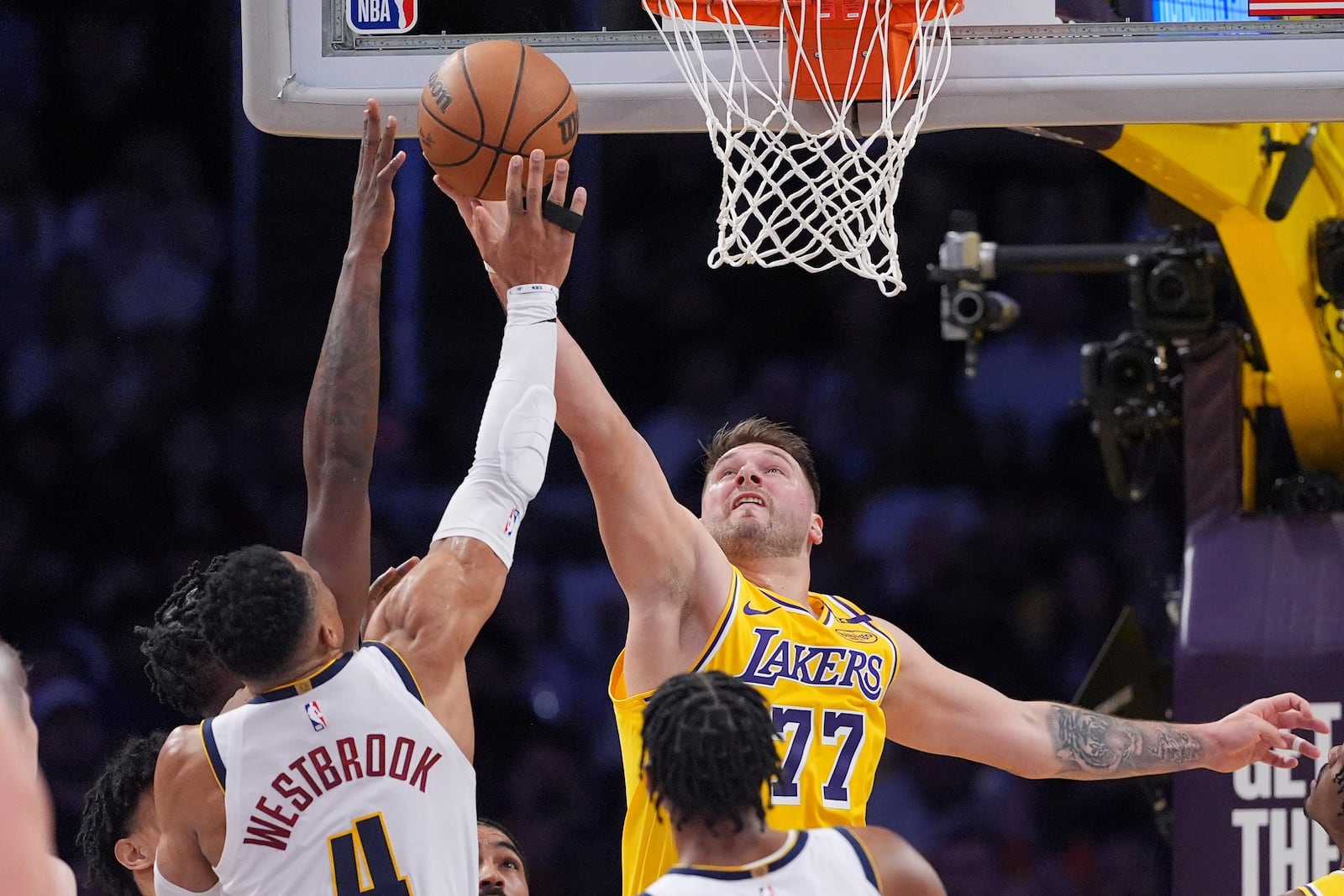 Denver Nuggets guard Russell Westbrook, left, and Los Angeles Lakers guard Luka Doncic reach for a rebound during the first half of an NBA basketball game Wednesday, March 19, 2025, in Los Angeles. (AP Photo/Mark J. Terrill)