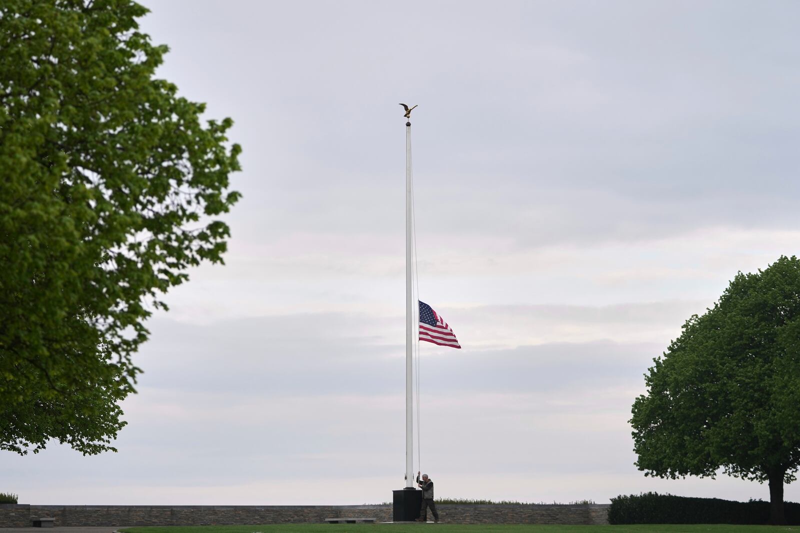 A groundsman raises the U.S. flag to half-staff, in honor of Pope Francis who has died at the age of 88, at the Second Word War Henri-Chapelle American military cemetery in Thimister-Clermont, Belgium, Tuesday, April 22, 2025.