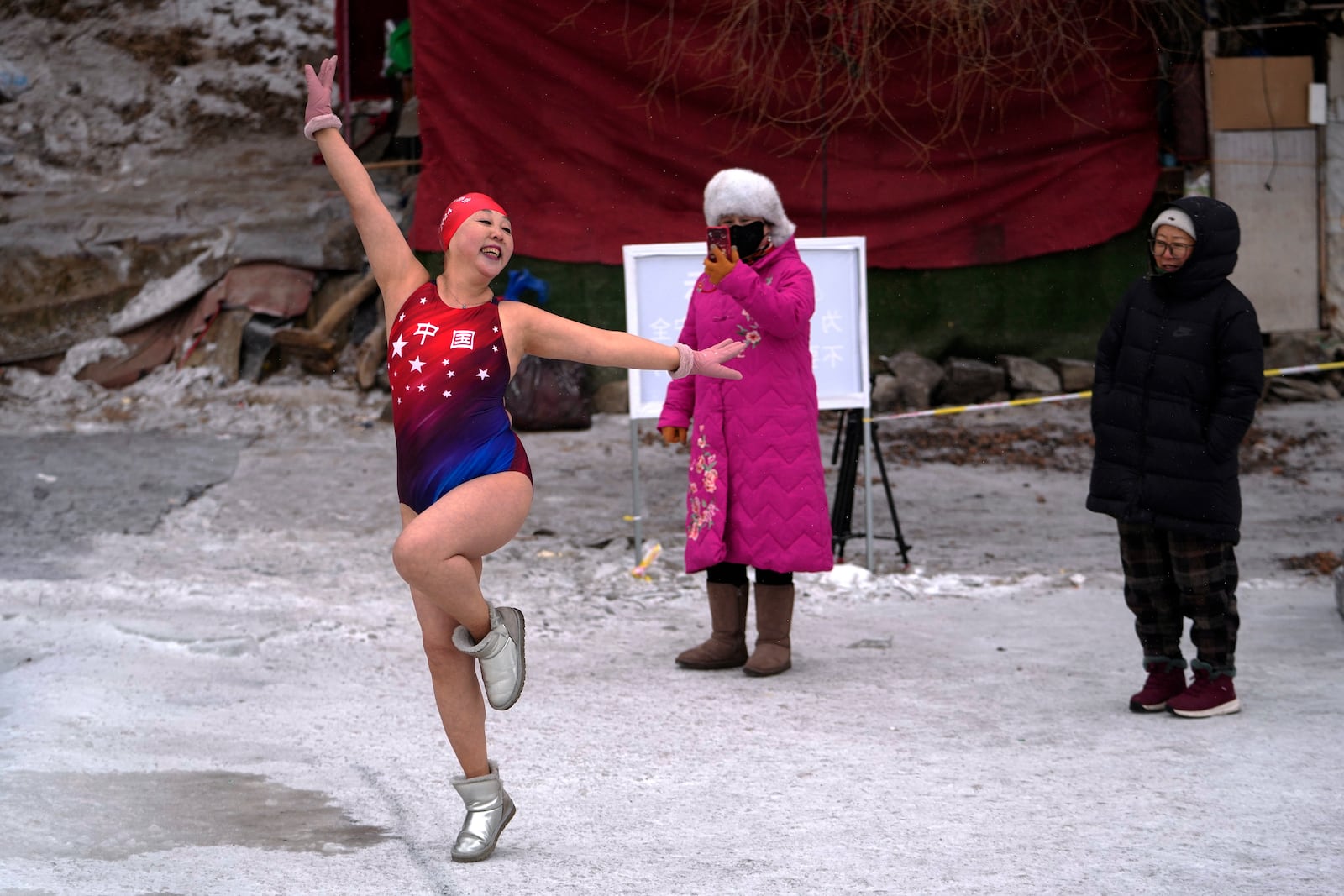 Residents in winter clothing watch Yu Xiaofeng pose as she prepares to swim in a pool carved from ice on the frozen Songhua river in Harbin in northeastern China's Heilongjiang province, Tuesday, Jan. 7, 2025. (AP Photo/Andy Wong)