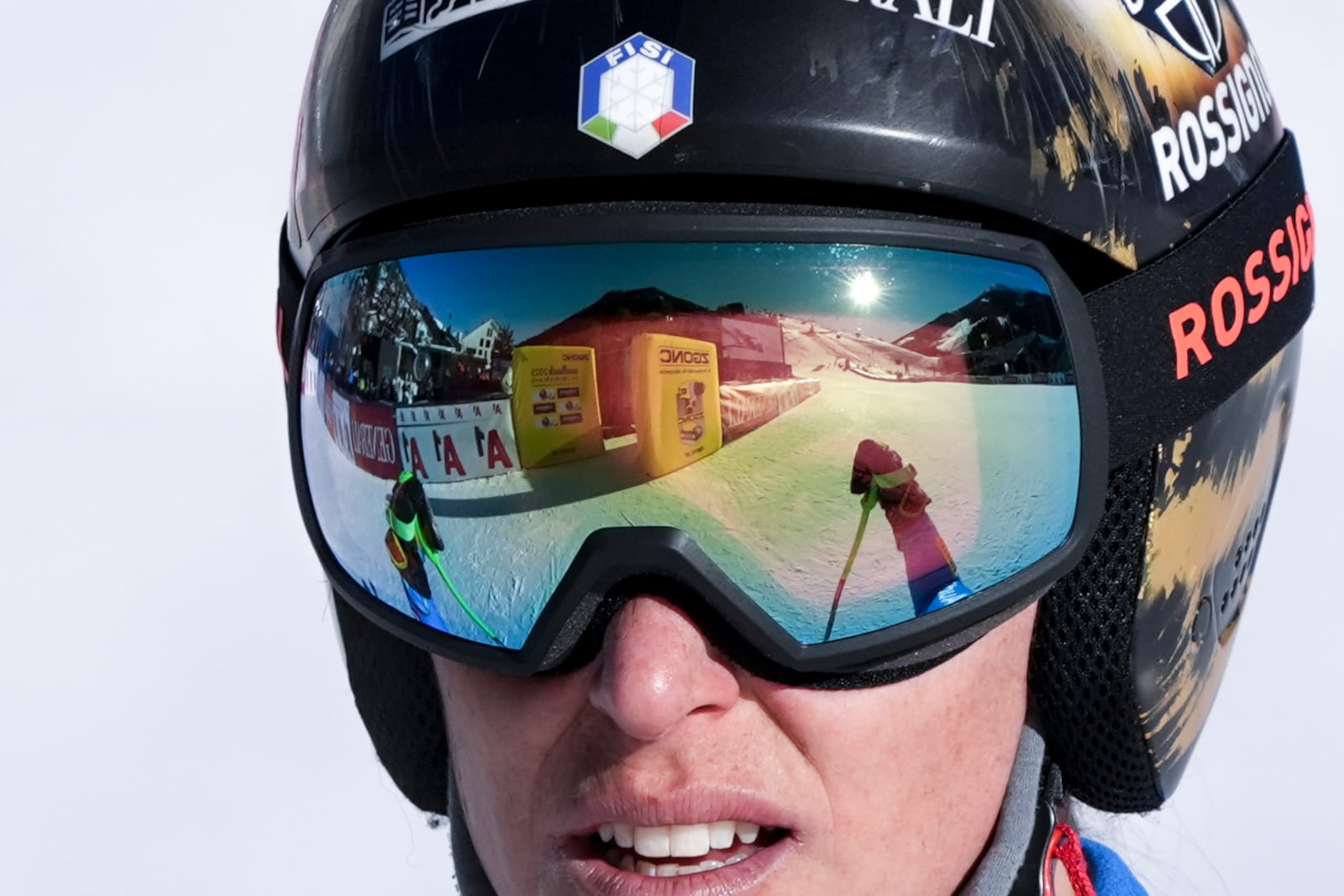 The finish area is reflected in the goggles of Italy's Federica Brignone after she completed an alpine ski, women's World Championship downhill training, in Saalbach-Hinterglemm, Austria, Tuesday, Feb. 4, 2025. (AP Photo/Giovanni Auletta)