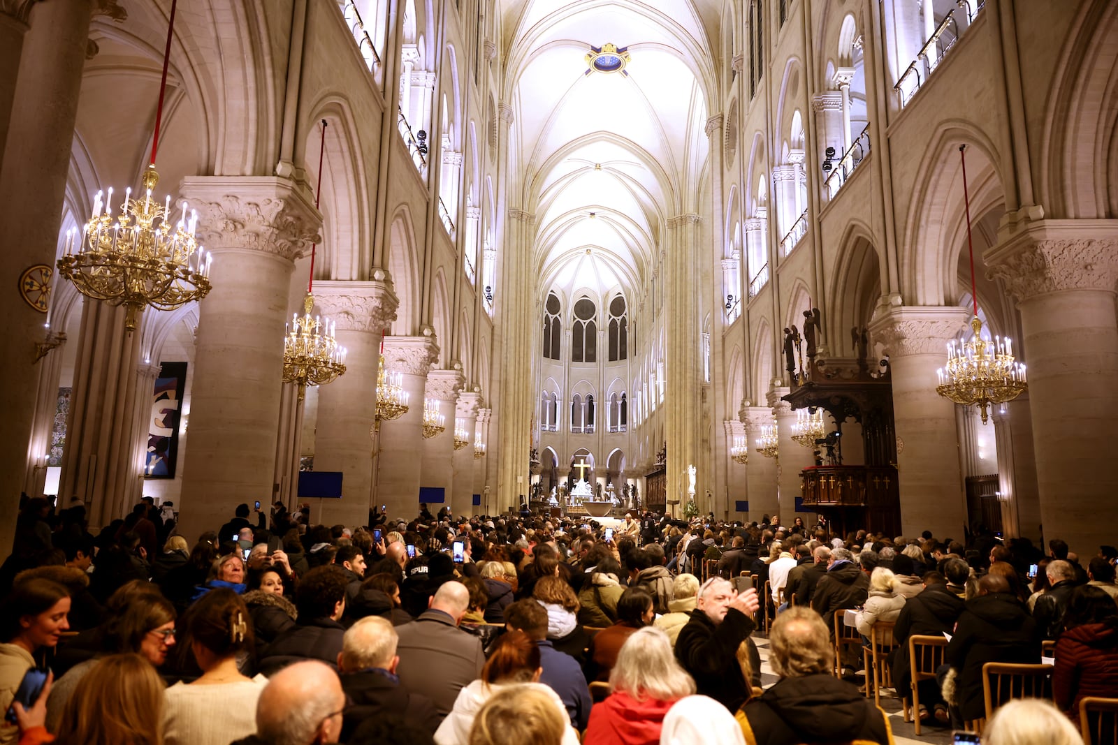 Faithful sit before the mass at Notre Dame Cathedral as the monuments hosts Christmas Eve services for the first time since a devastating 2019 fire, Tuesday, Dec. 24, 2024 in Paris. (AP Photo/Thomas Padilla)