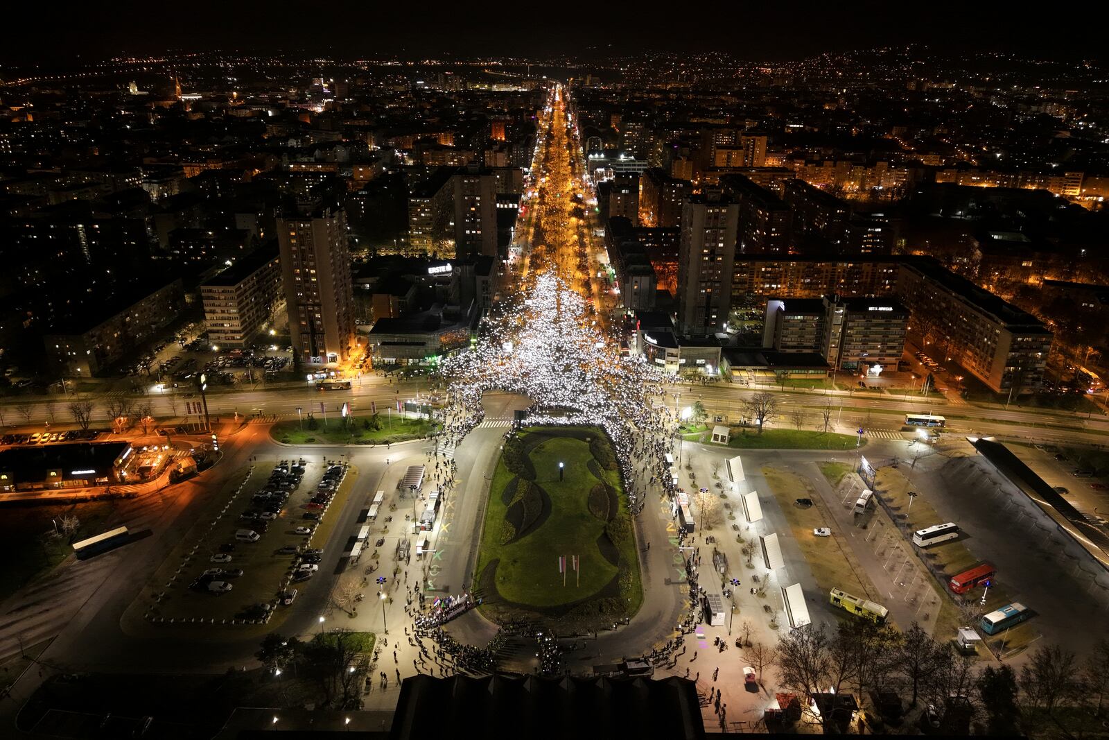 An aerial view of people hold up their mobile phone lights during a protest in front of a railway station where the collapse of a concrete canopy killed 15 people more than two months ago, in Novi Sad, Serbia, Friday, Jan. 31, 2025. (AP Photo/Armin Durgut)