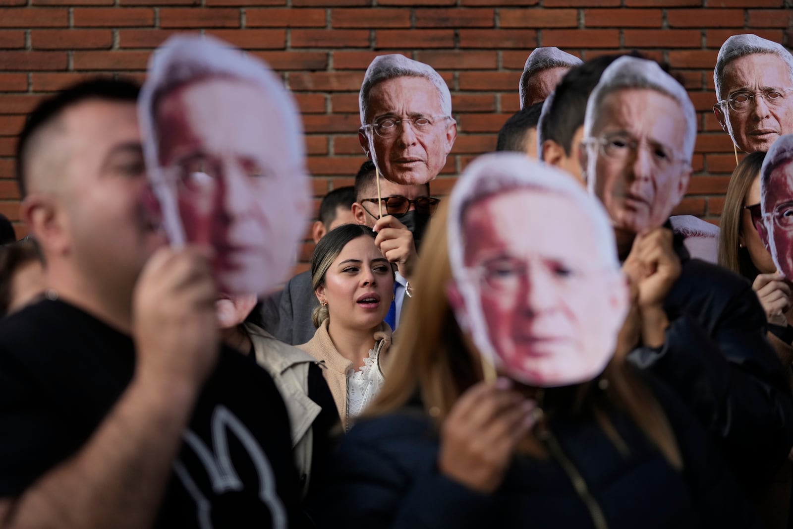 Supporters of Colombia's former President Alvaro Uribe hold cutouts of his portrait outside the court where he is attending a hearing on charges of witness tampering and bribery in Bogota, Colombia, Monday, Feb. 10, 2025. (AP Photo/Fernando Vergara)