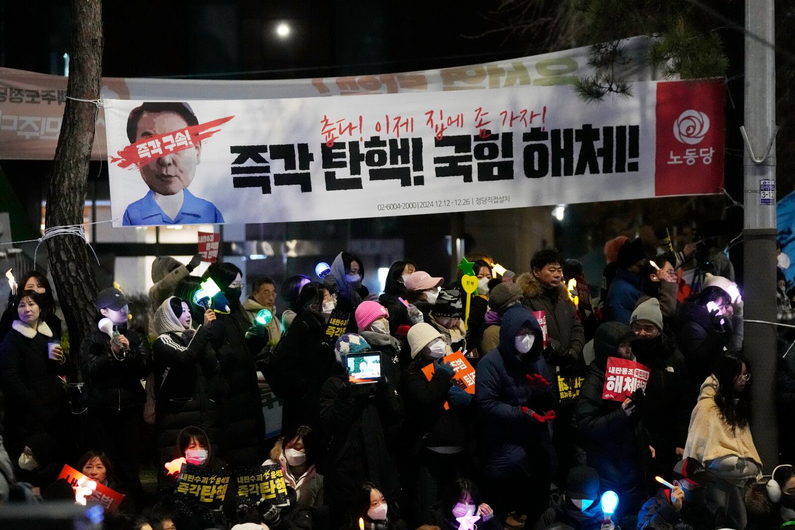 Participants attend a rally to demand South Korean President Yoon Suk Yeol's impeachment outside the National Assembly in Seoul, South Korea, Friday, Dec. 13, 2024. The signs read "Immediately impeachment, disband the ruling People Power Party." (AP Photo/Ahn Young-joon)