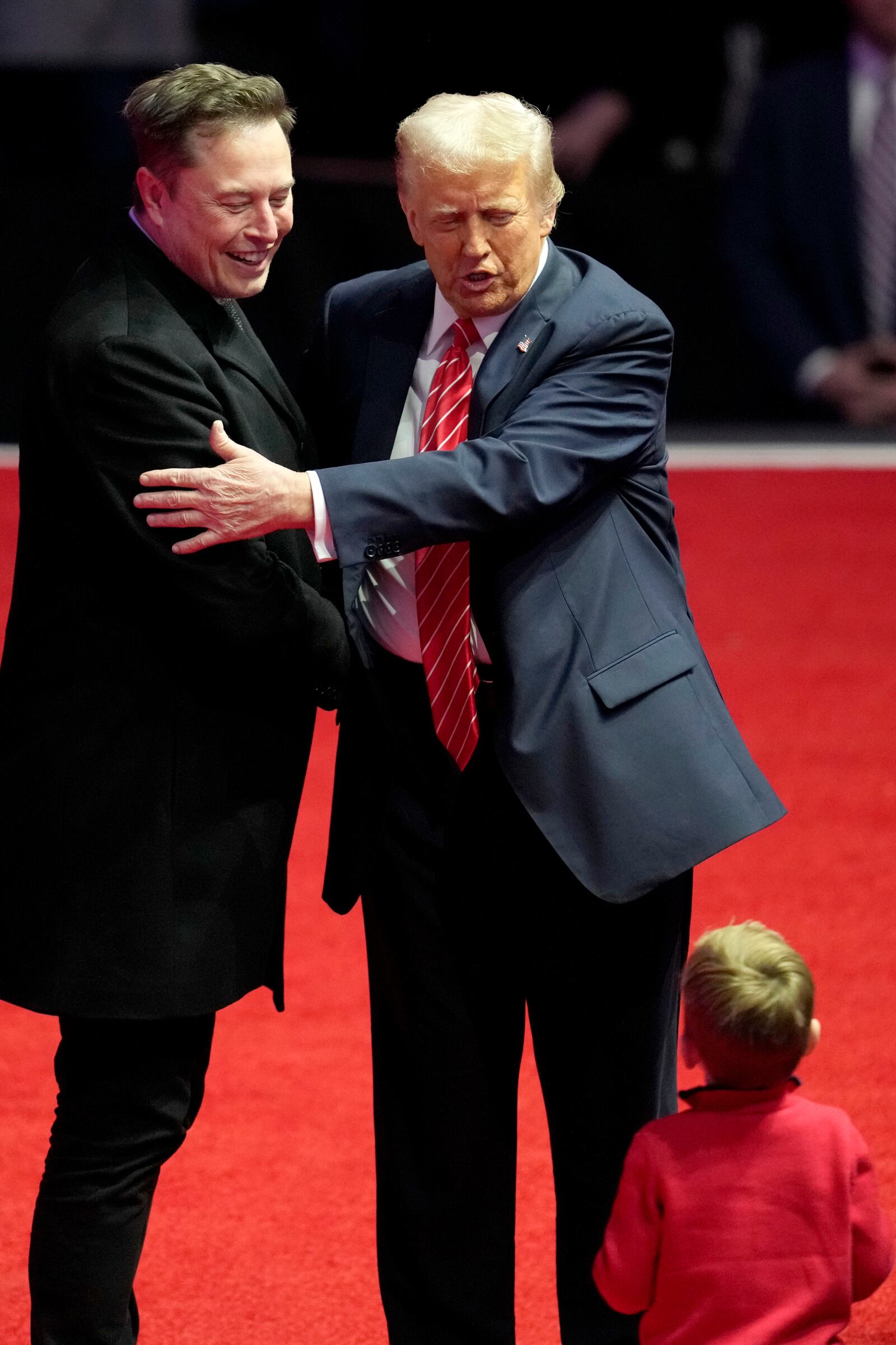 Elon Musk, left, and President-elect Donald Trump embrace as they look at Musk's son X Æ A-Xii, at a rally ahead of the 60th Presidential Inauguration, Sunday, Jan. 19, 2025, in Washington. (AP Photo/Alex Brandon)