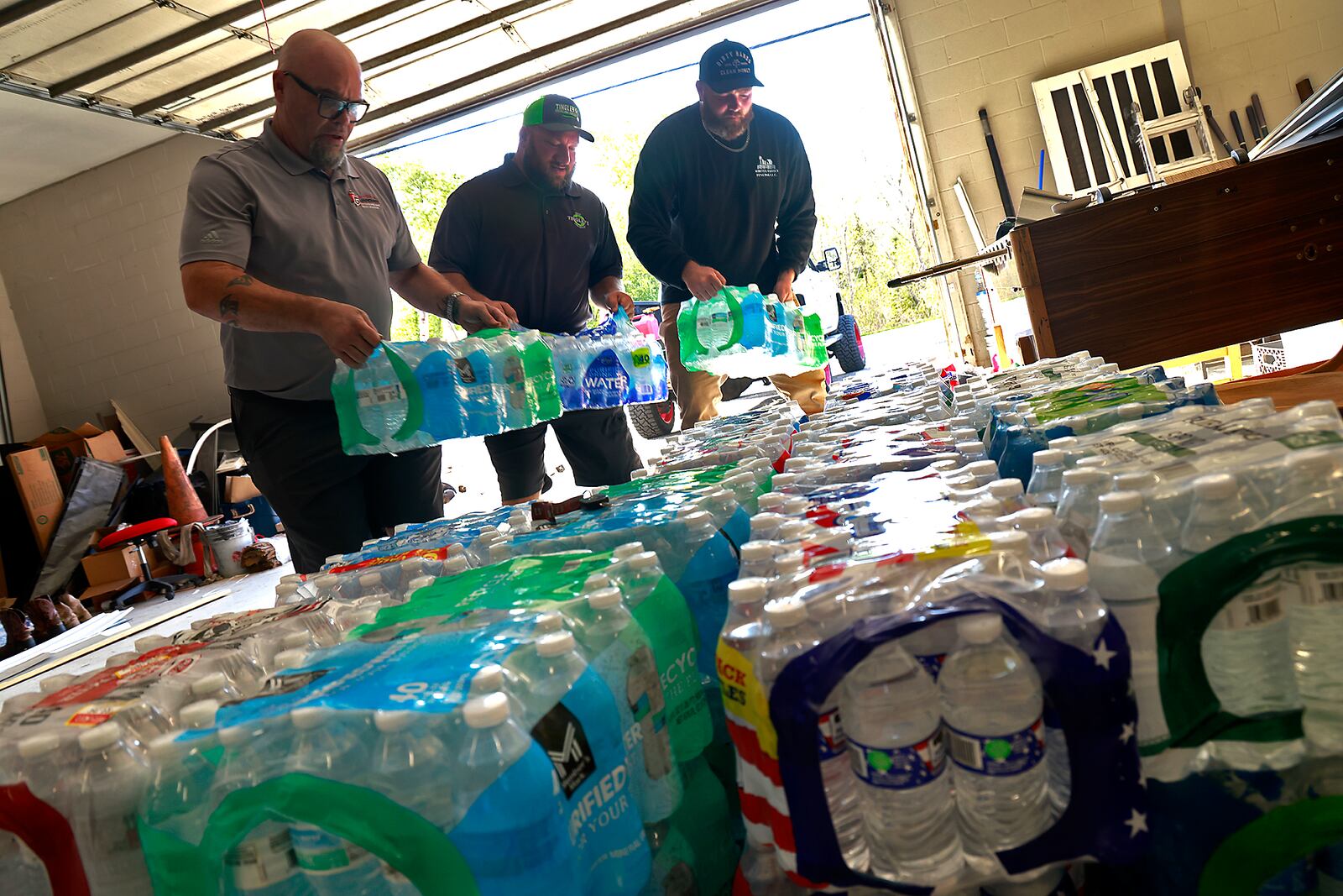 Casey Tingley, president of Ohio Hope Builders, center, Mark Houseman from Guardian Exteriors and Restoration, left, and Bryce White from Whites Family Fencing, unload supplies for the storm victims down south Tuesday, Oct. 1, 2024. BILL LACKEY/STAFF