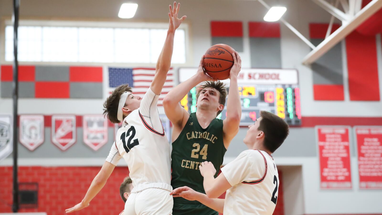 Catholic Central High School senior Tyler Galluch shoots the ball over Cedarville junior Tyler Cross (left) and senior Noah Burr (right) during their D-IV district semifinal game on Saturday night at Troy High School. CONTRIBUTED PHOTO BY MICHAEL COOPER