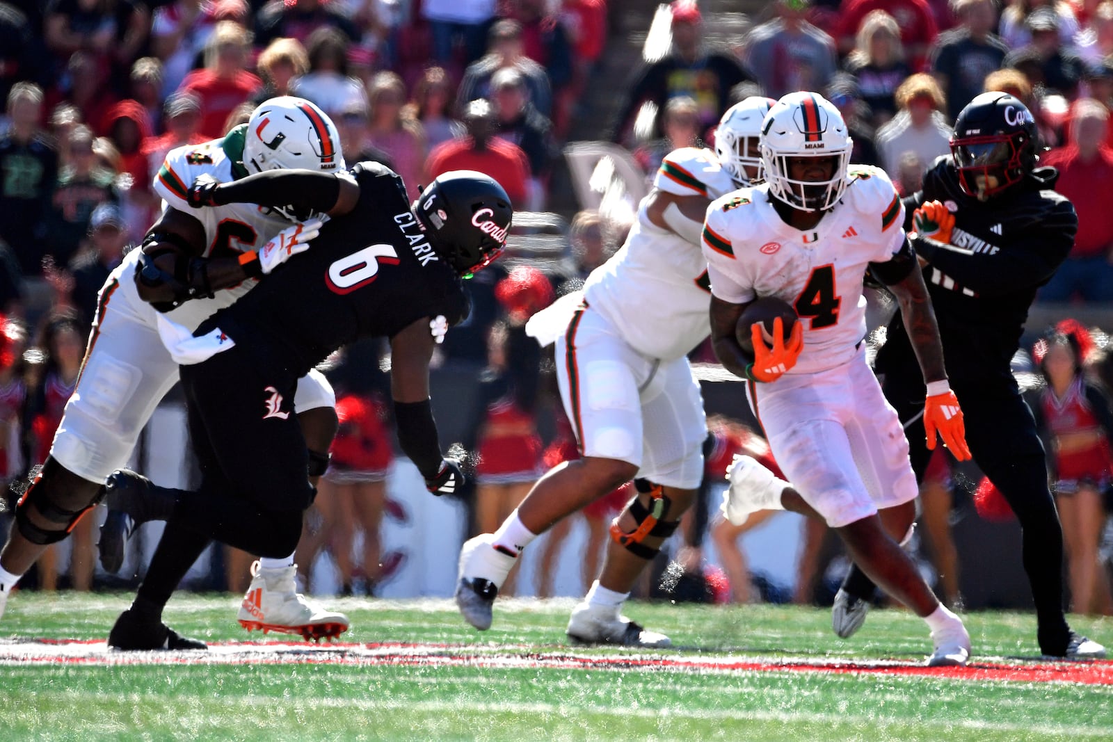 Miami running back Mark Fletcher Jr. (4) runs away from the Louisville linebacker Stanquan Clark (6) during the first half of an NCAA college football game in Louisville, Ky., Saturday, Oct. 19, 2024. Miami won 52-45. (AP Photo/Timothy D. Easley)