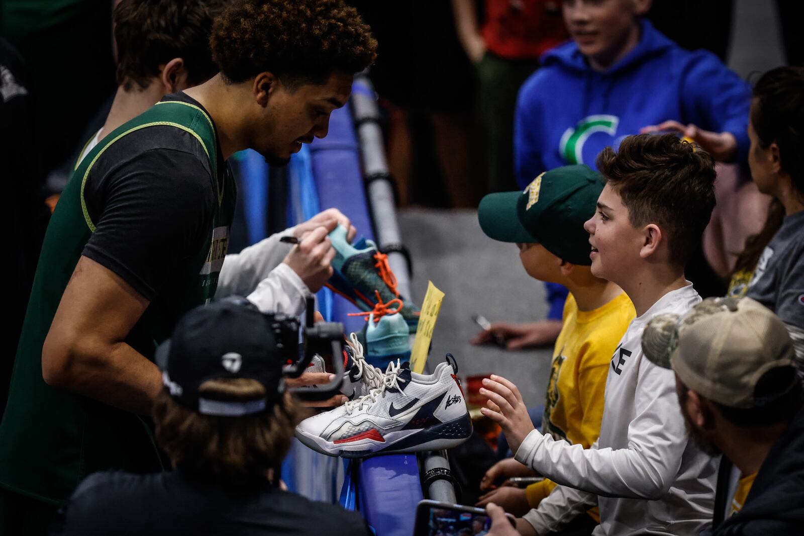 WSU forward/center CJ Wilbourn signs basketball shoes for brothers Abe and Levi Tew, both from Dayton, at a practice before the First Four.