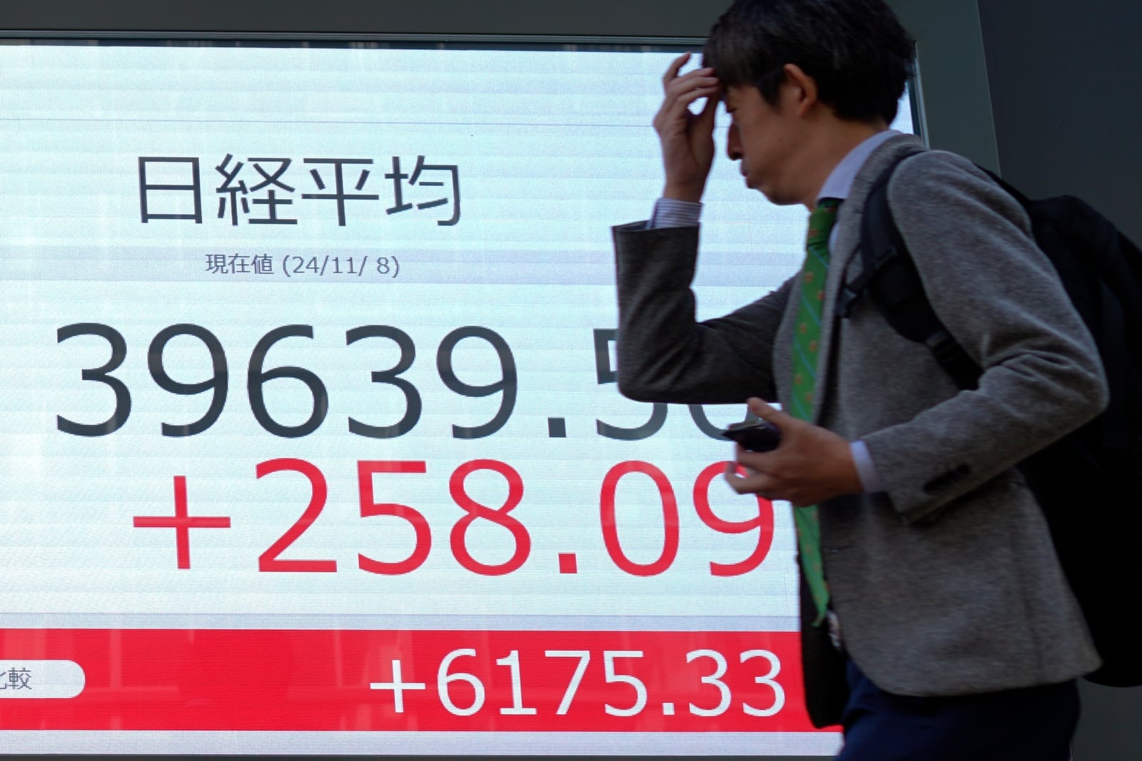 A person walks in front of an electronic stock board showing Japan's Nikkei index at a securities firm Friday, Nov. 8, 2024, in Tokyo. (AP Photo/Eugene Hoshiko)