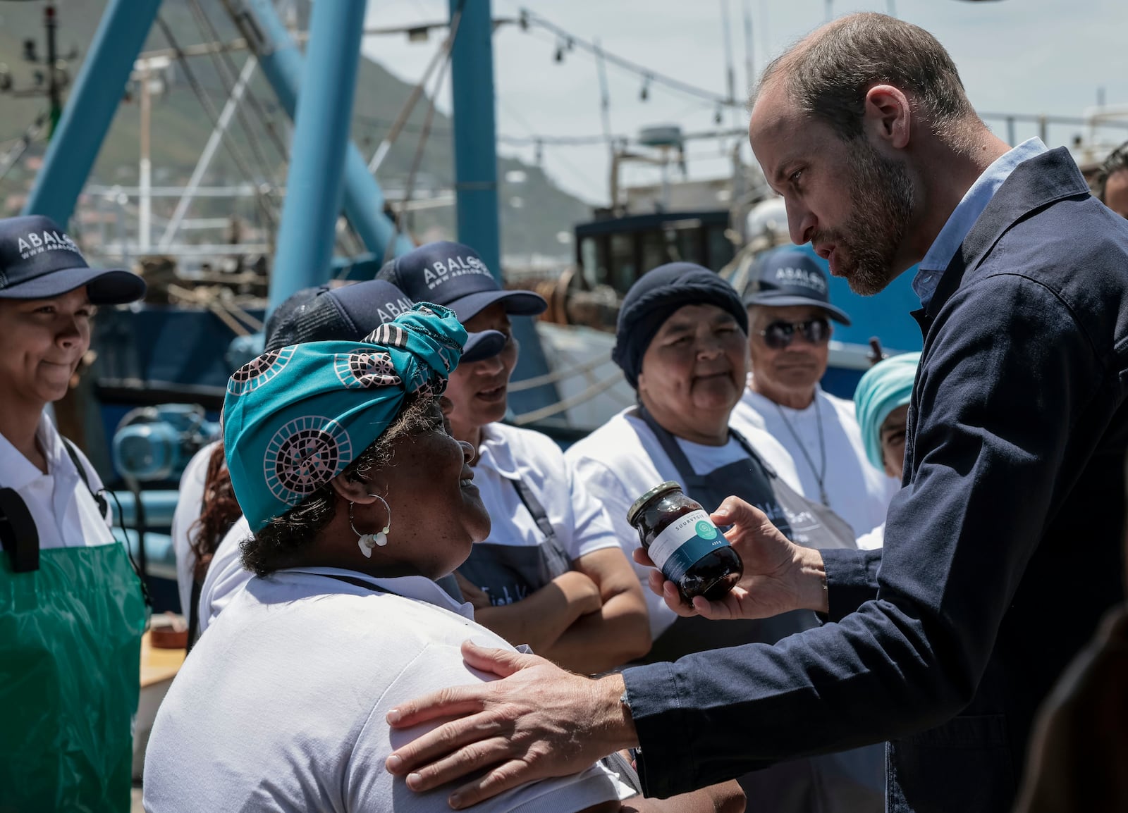 Britain's Prince William, the Prince of Wales receives a gift from a local, at Kalk Bay Harbour, near Cape Town, Thursday, Nov. 7, 2024. (Gianluigi Guercia/Pool Photo via AP)