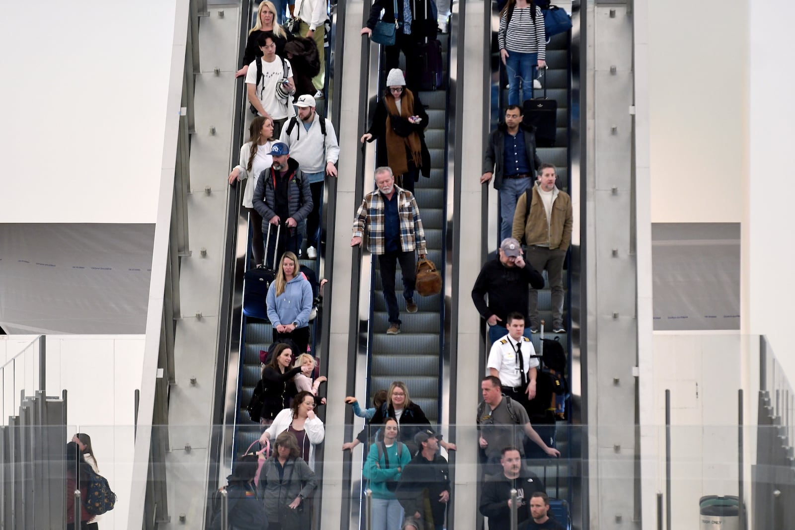 Passengers descend an escalator at Denver International Airport on Friday, March 14, 2025, in Denver. (AP Photo/ Thomas Peipert)