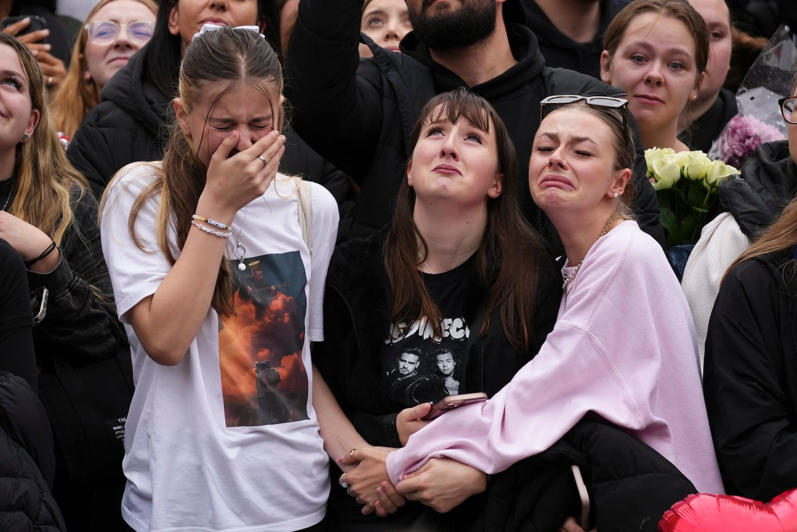 Fans react as they gather near the Peter Pan statue in Hyde Park, London to pay tribute to late British singer Liam Payne, former member of the British pop band One Direction, Sunday, Oct. 20, 2024. (Photo by Scott A Garfitt/Invision/AP)