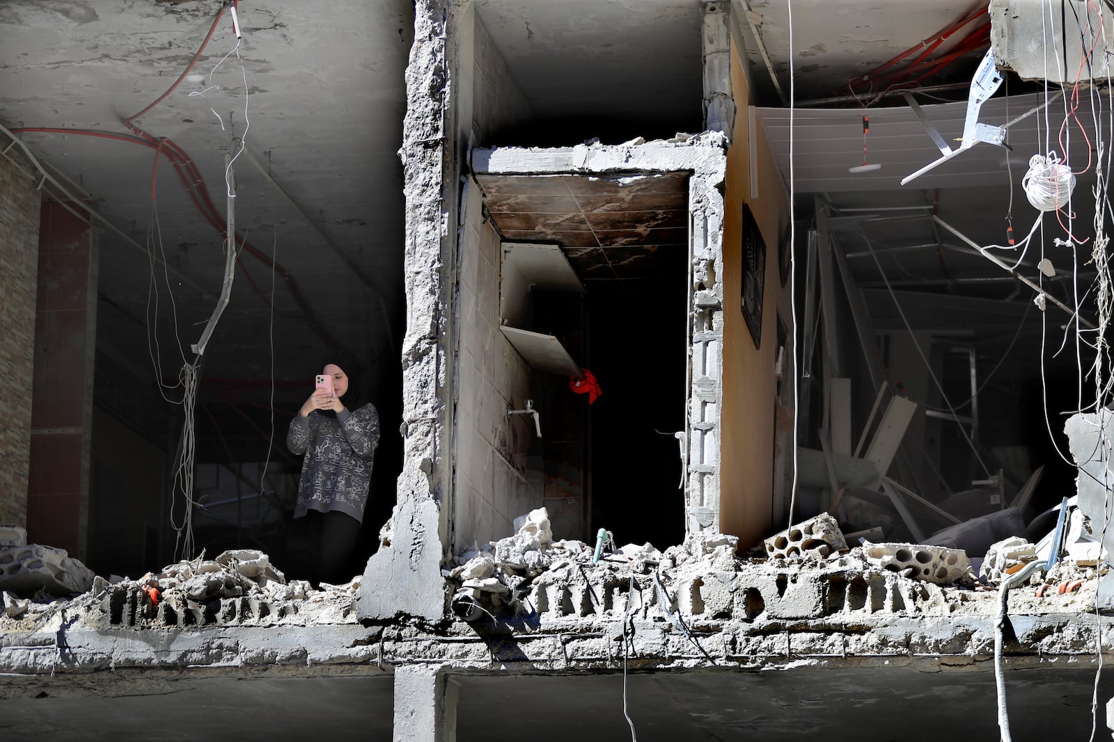 A woman takes pictures by her mobile phone, as she stands at a destroyed apartment that was hit by an Israeli airstrike, in Tyre, south Lebanon, Thursday, Oct. 24, 2024. (AP Photo/Mohammed Zaatari)