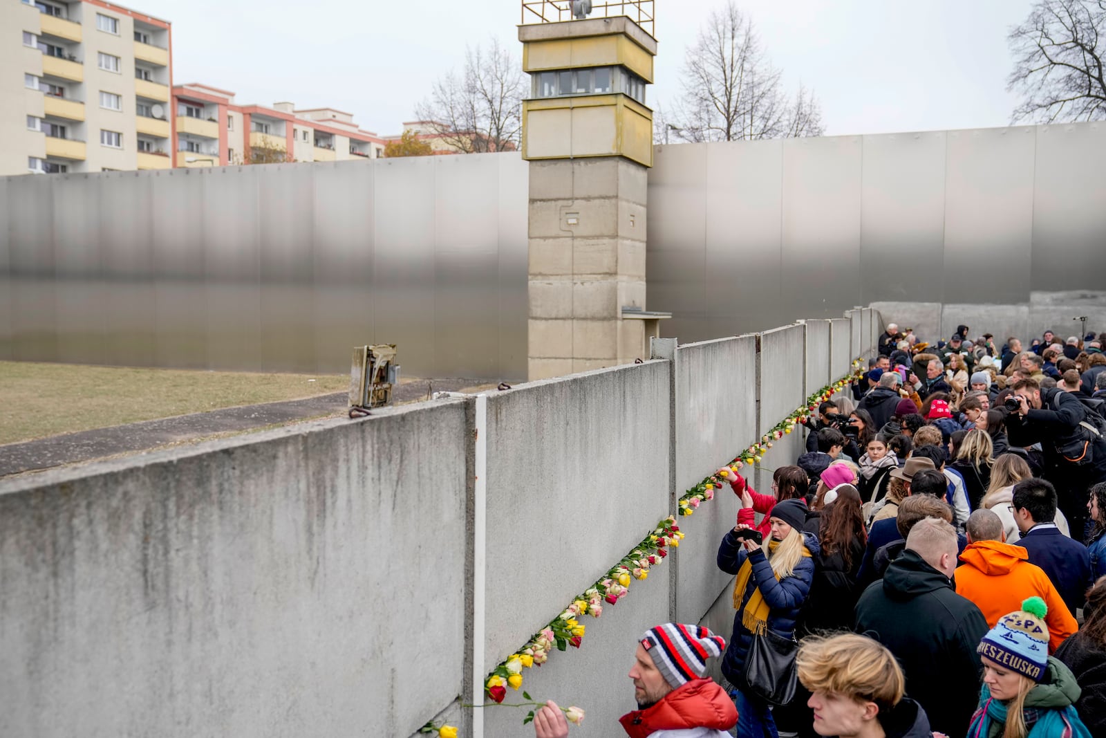 People attend a flower laying ceremony on occasion of the 35th wall anniversary at the grounds of the Berlin Wall Memorial, Berlin, Germany, Saturday, Nov.9, 2024. (AP Photo/Ebrahim Noroozi)