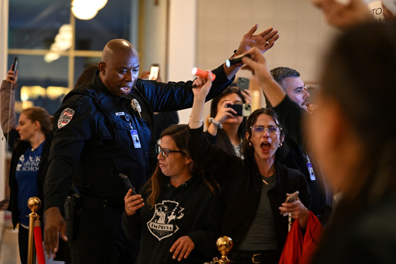 A general assembly police officer escorts protestors after the Republican-dominated North Carolina House convened and completed the override of Democratic Gov. Roy Cooper's veto of a bill that aims to weaken the powers of Cooper's soon-to-be successor and other Democratic statewide winners in the Nov. 5 elections, Wednesday, Dec. 11, 2024, in Raleigh, N.C. (AP Photo/Matt Kelley)