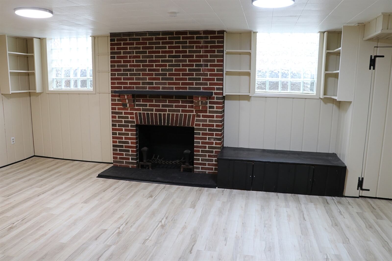 The fireplace has a wood-beam mantel and brick hearth. A bench seat with storage is next to the fireplace.