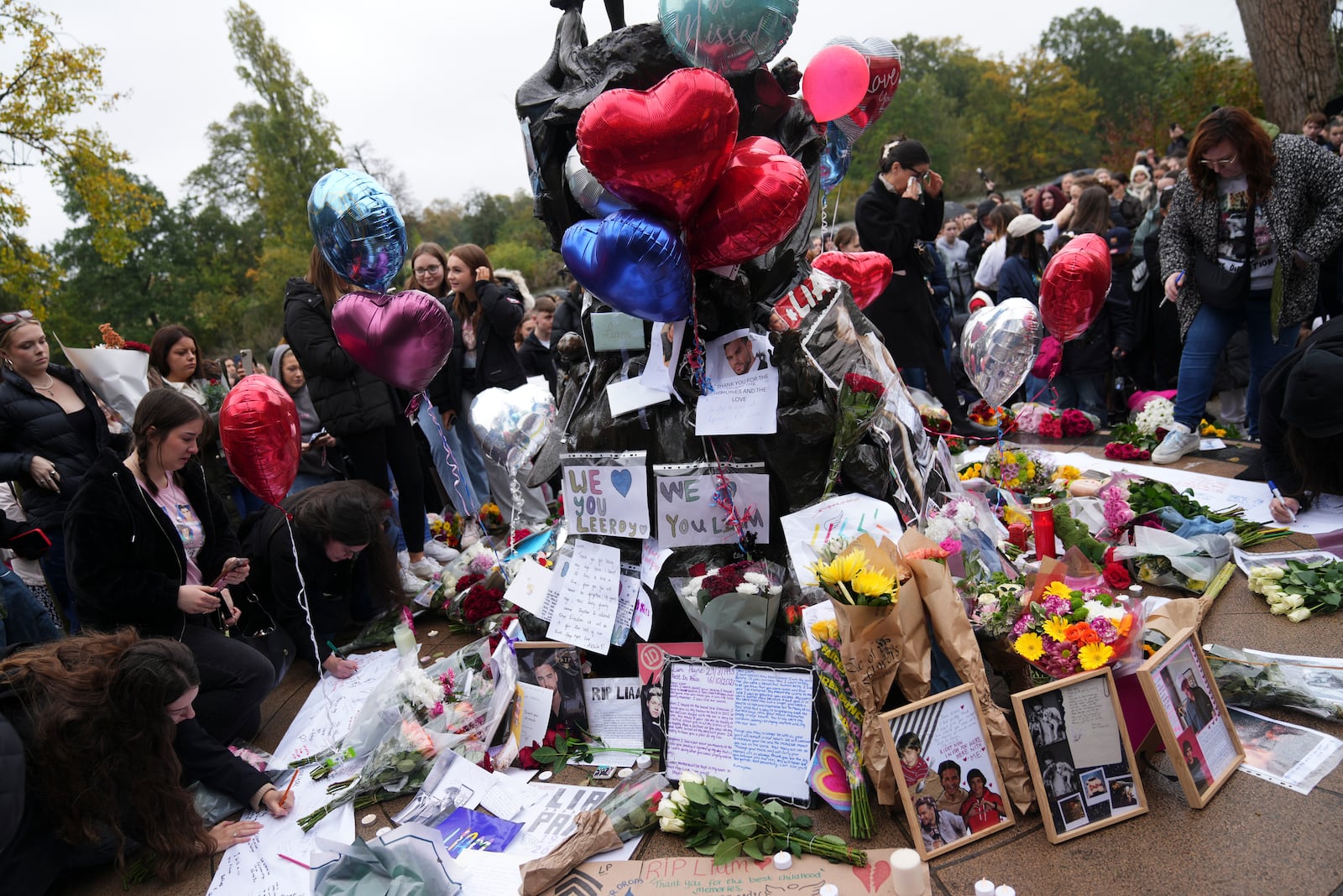 Fans gather near the Peter Pan statue in Hyde Park, London to pay tribute to late British singer Liam Payne, former member of the British pop band One Direction, Sunday, Oct. 20, 2024. (Photo by Scott A Garfitt/Invision/AP)