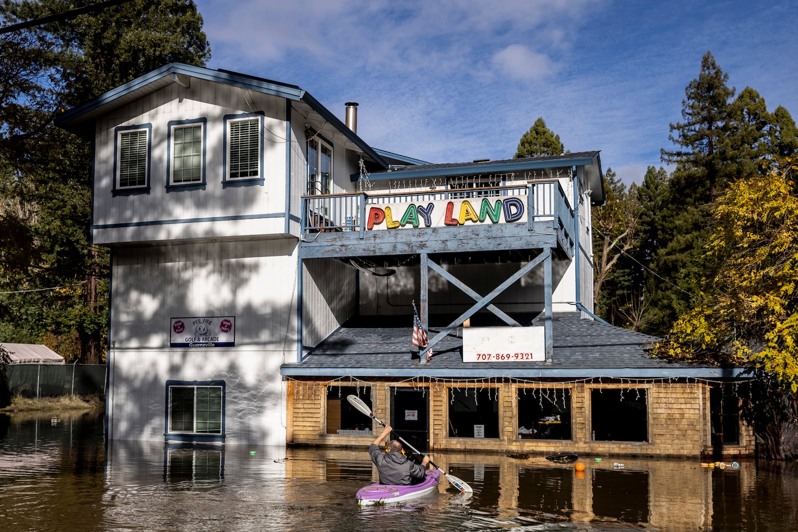 Tim Bosque, owner of Pee Wee Golf & Arcade, kayaks in flood water to recover items that floated away after a major storm in Guerneville, Calif., Saturday, Nov. 23, 2024. (Stephen Lam/San Francisco Chronicle via AP)