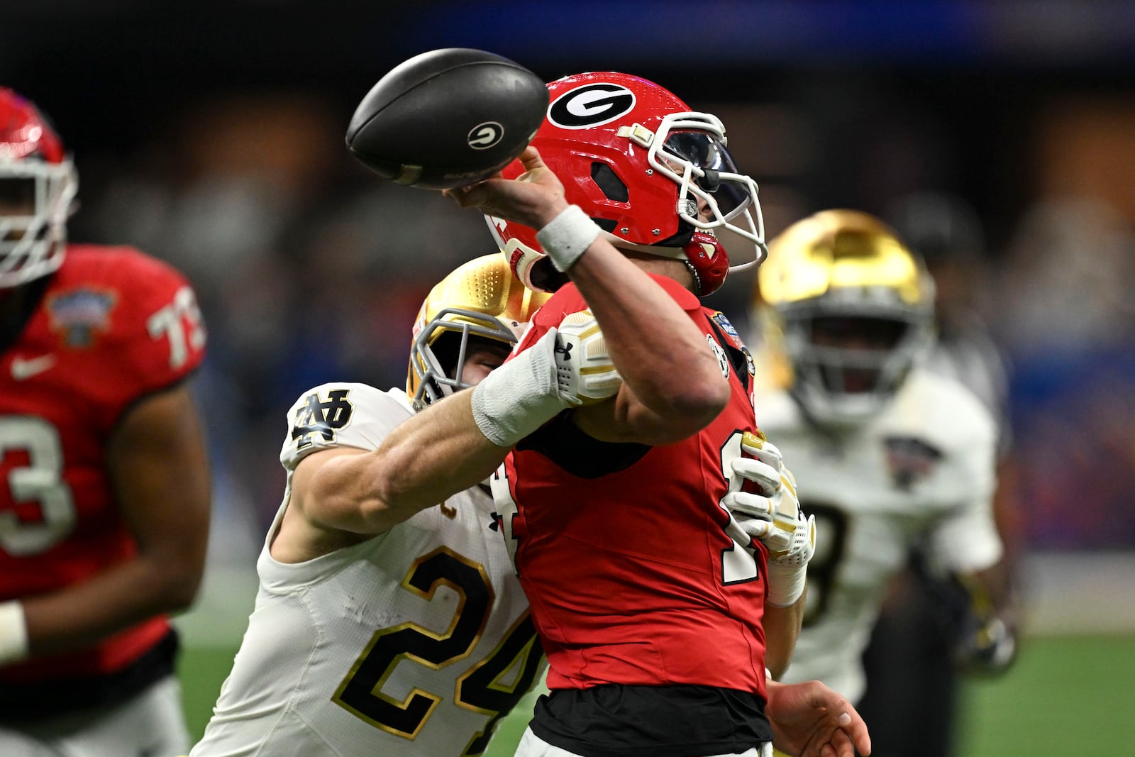 Georgia quarterback Gunner Stockton fumbles as he is hit by Notre Dame linebacker Jack Kiser (24) during the first half in the quarterfinals of a College Football Playoff, Thursday, Jan. 2, 2025, in New Orleans. (AP Photo/Matthew Hinton)