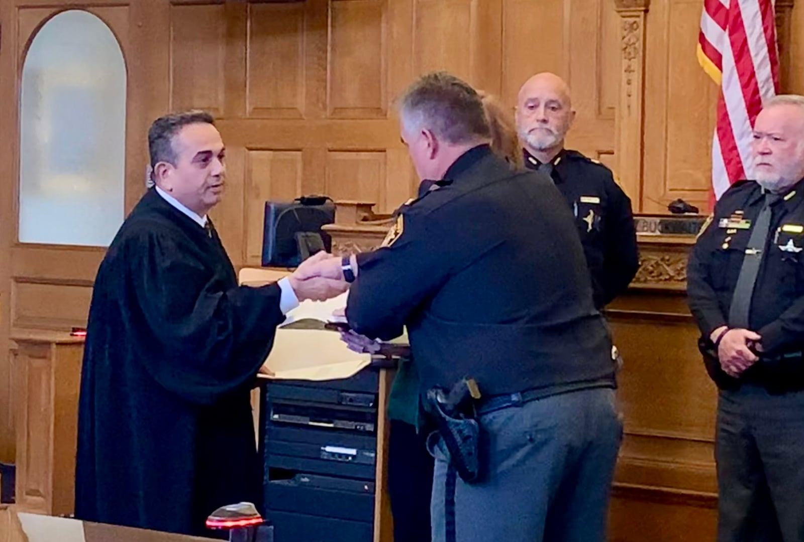 Judge Adolfo Tornichio shakes hands with Scott Anger after swearing him in as acting Sheriff in Greene County.