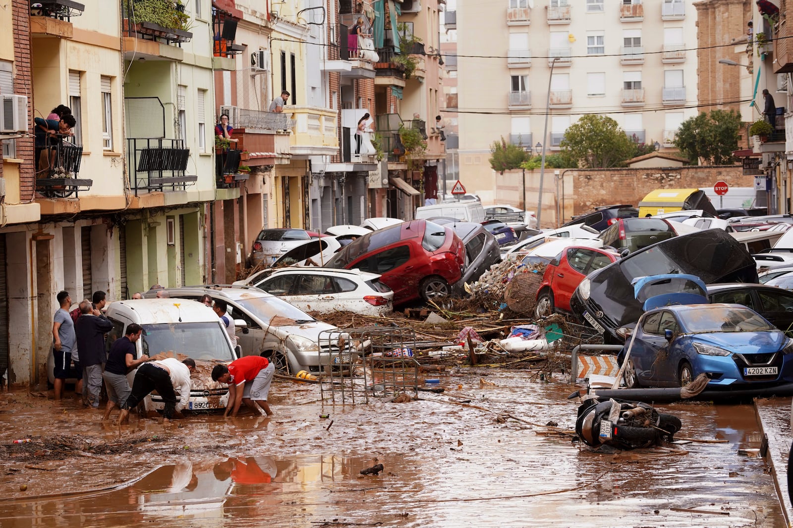 Residents look at cars piled up after being swept away by floods in Valencia, Spain, Wednesday, Oct. 30, 2024. (AP Photo/Alberto Saiz)