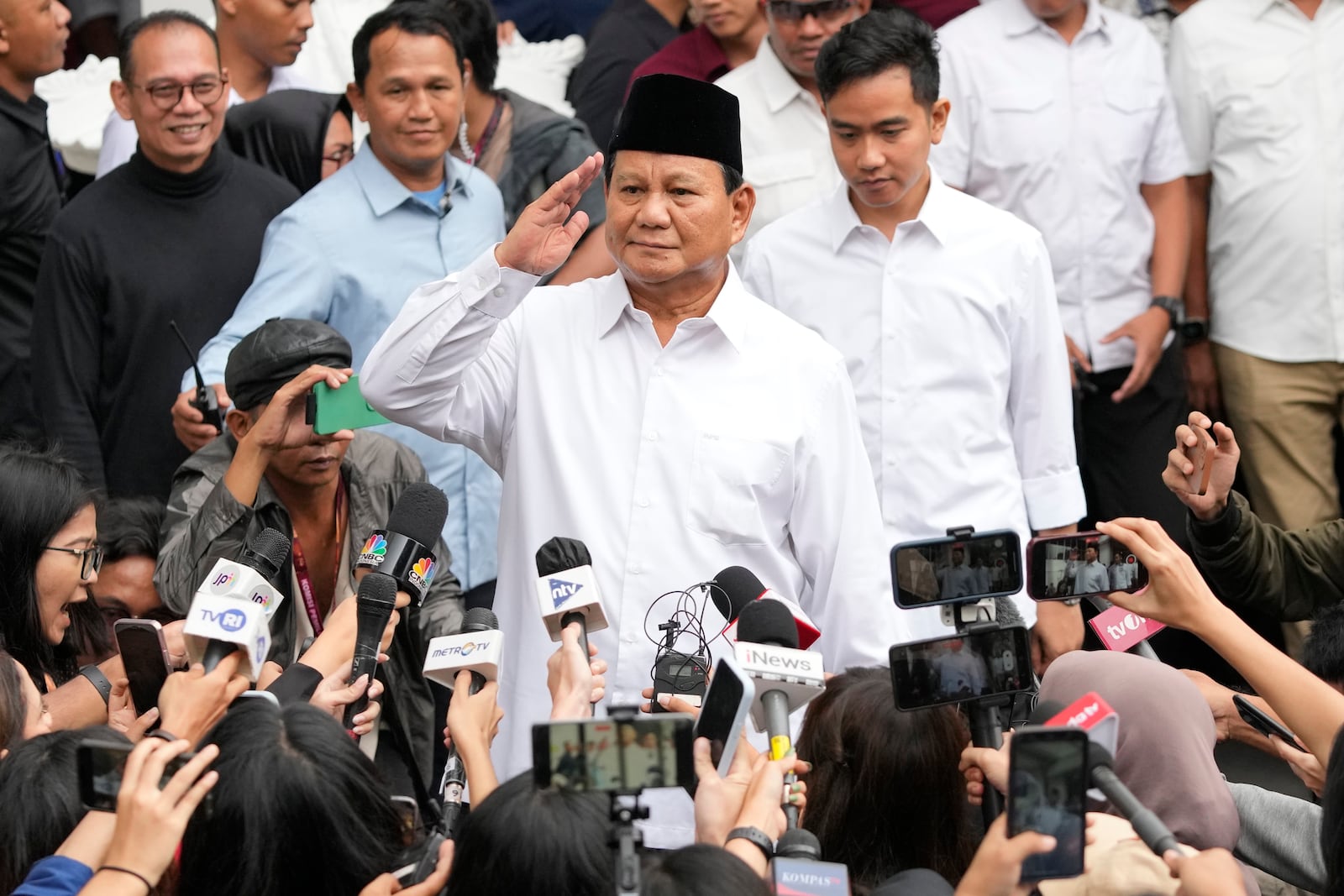 FILE - Indonesian Defense Minister and president-elect Prabowo Subianto, center, salutes to journalists in front of his running mate Gibran Rakabuming Raka, rear center, the eldest son of Indonesian President Joko Widodo, during their formal declaration as president and vice president-elect at the General Election Commission building in Jakarta, Indonesia, Wednesday, April 24, 2024. (AP Photo/Achmad Ibrahim, File)