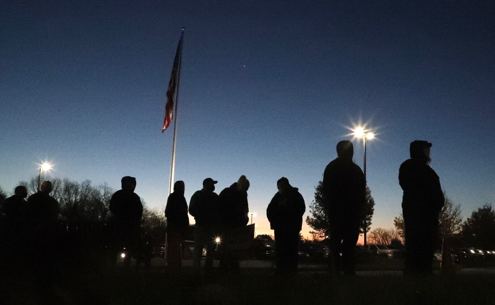 Voters stand in line outside Tecumseh High School in New Carlisle as the sun rises Tuesday morning. BILL LACKEY/STAFF