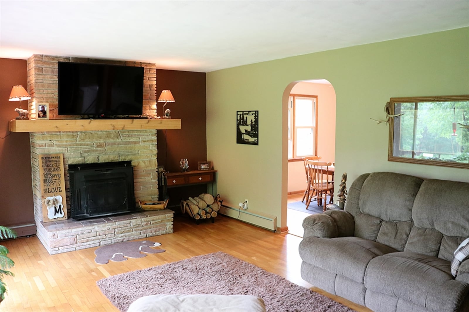 A stack-stone fireplace has a wood-burning insert, stone hearth and wood-beam mantel. Matching stack-stone accents the wall space near the front door and open stairwell to the bedroom-level. Contributed photo