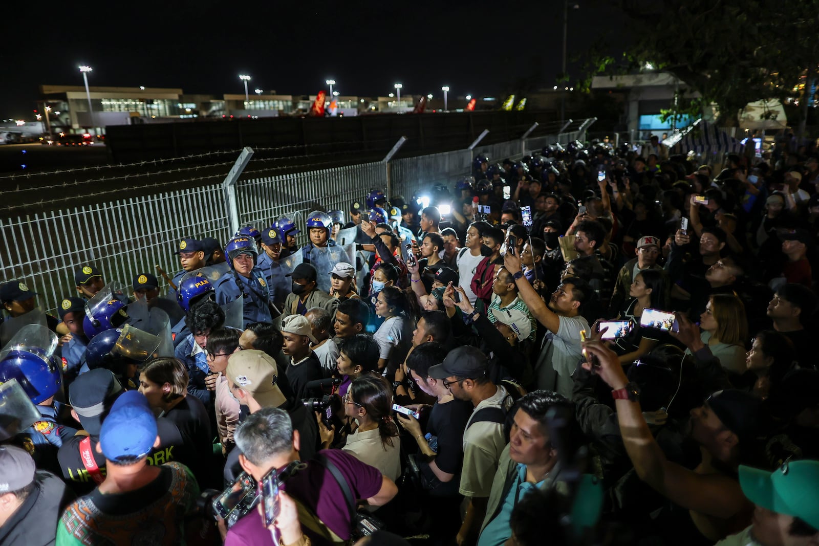 Supporters of former President Rodrigo Duterte rush to the fence of the Villamor Air Base in Manila, Philippines, Wednesday March 11, 2025, upon learning that the plane taking the ex-president to The Hague has left the airport.(AP Photo/Gerard Carreon)