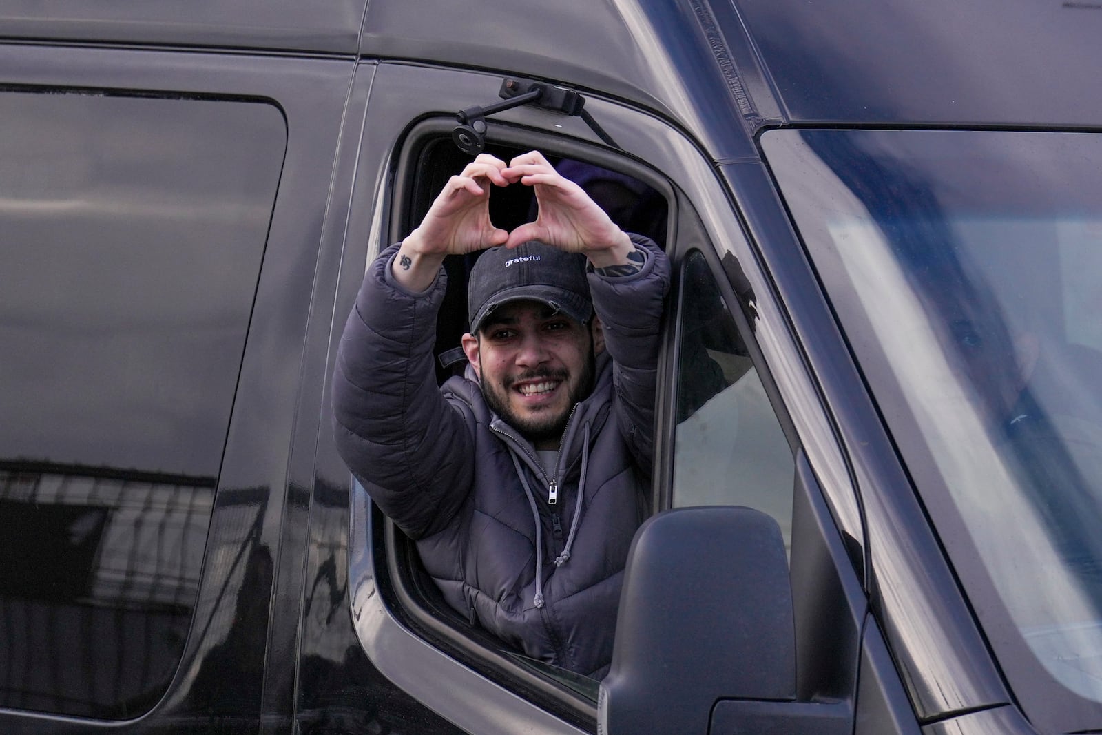 Freed Israeli hostage Eliya Cohen gestures from a van as he arrives at Beilinson hospital in Petah Tikva, Israel, after he was released from Hamas captivity in the Gaza Strip, Saturday, Feb. 22, 2025. (AP Photo/Ariel Schalit)