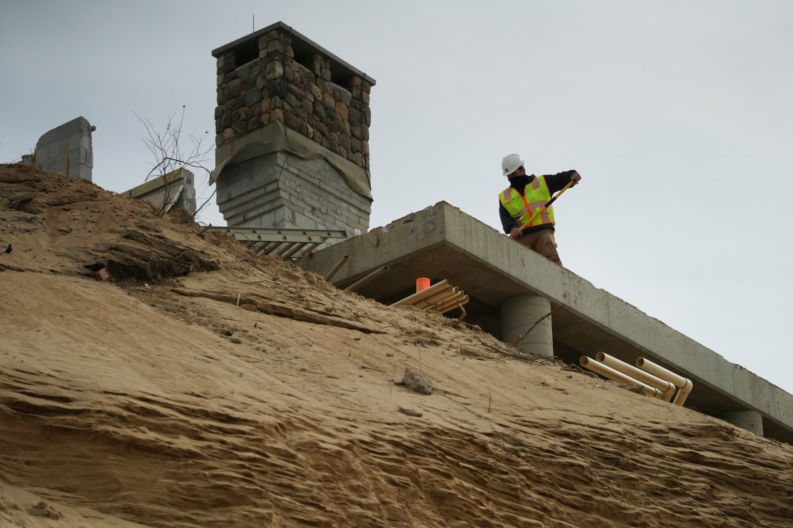 A home is demolished that sits atop of a sandy bluff overlooking a beach in Wellfleet, Mass., Tuesday, Feb. 25, 2025. (AP Photo/Andre Muggiati)