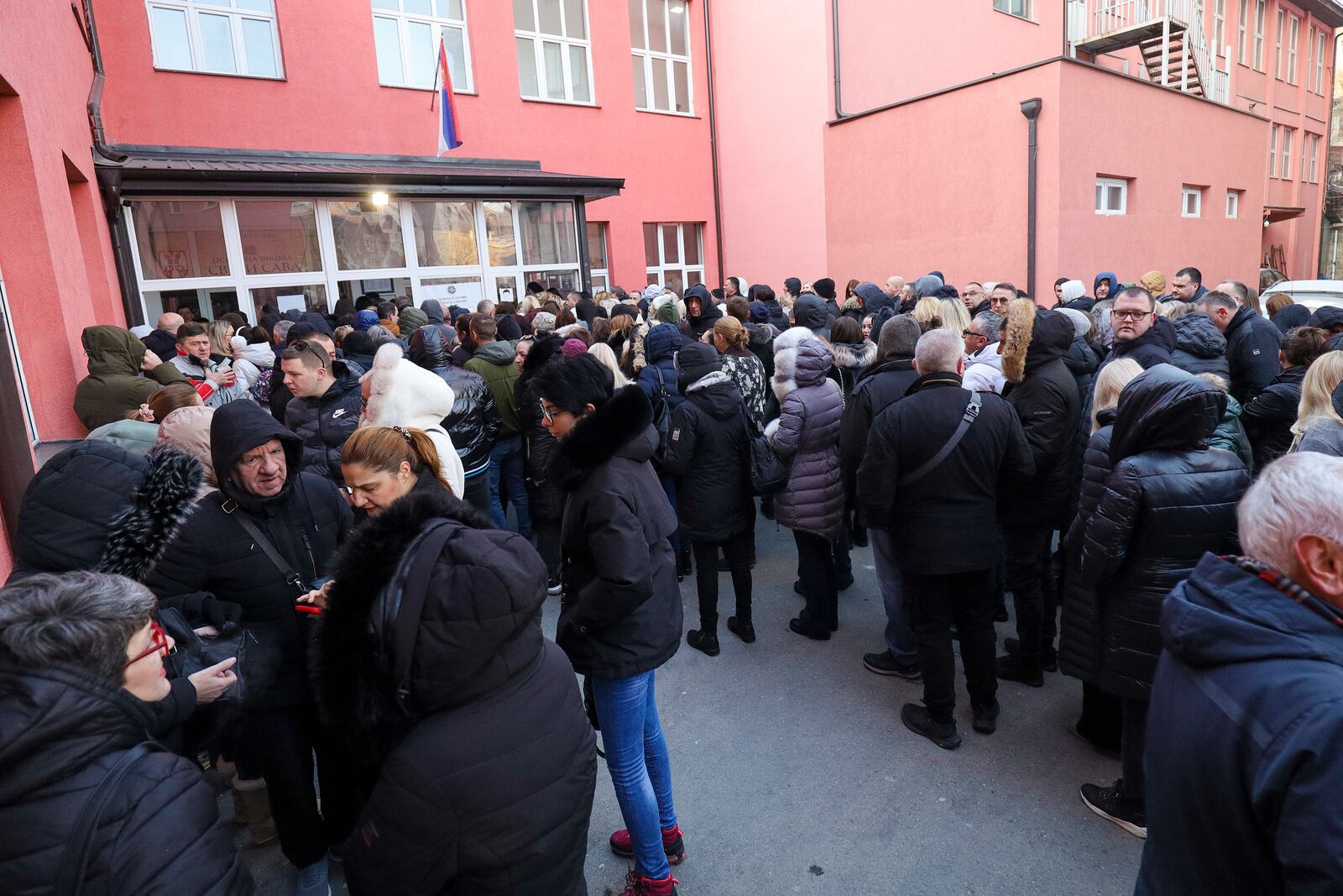 People wait in front of a polling station for a parliamentary election in the northern Serb-dominated part of ethnically divided town of Mitrovica, Kosovo, Sunday, Feb. 9, 2025. (AP Photo/Bojan Slavkovic)