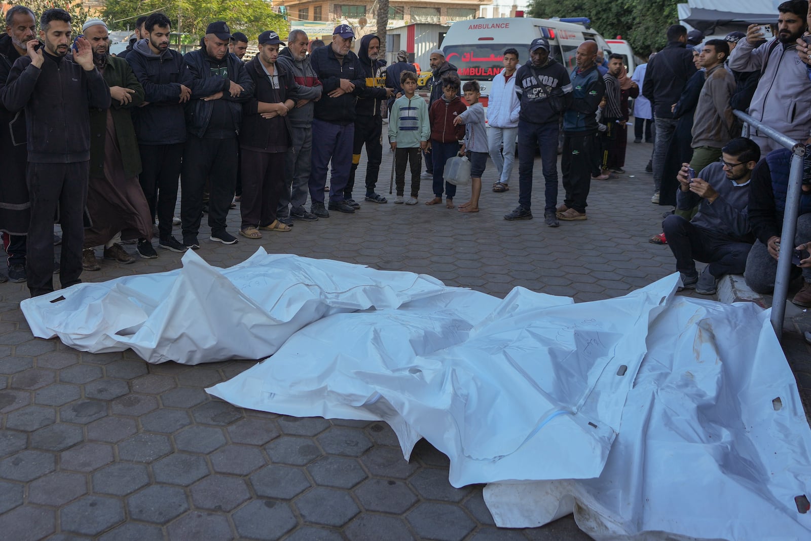 Men pray over the bodies of victims of an Israeli airstrike at the Nuseirat refugee camp during a funeral prayer outside the Al-Aqsa Martyrs hospital in Deir al-Balah, Gaza Strip, Saturday Dec. 21, 2024. (AP Photo/Abdel Kareem Hana)